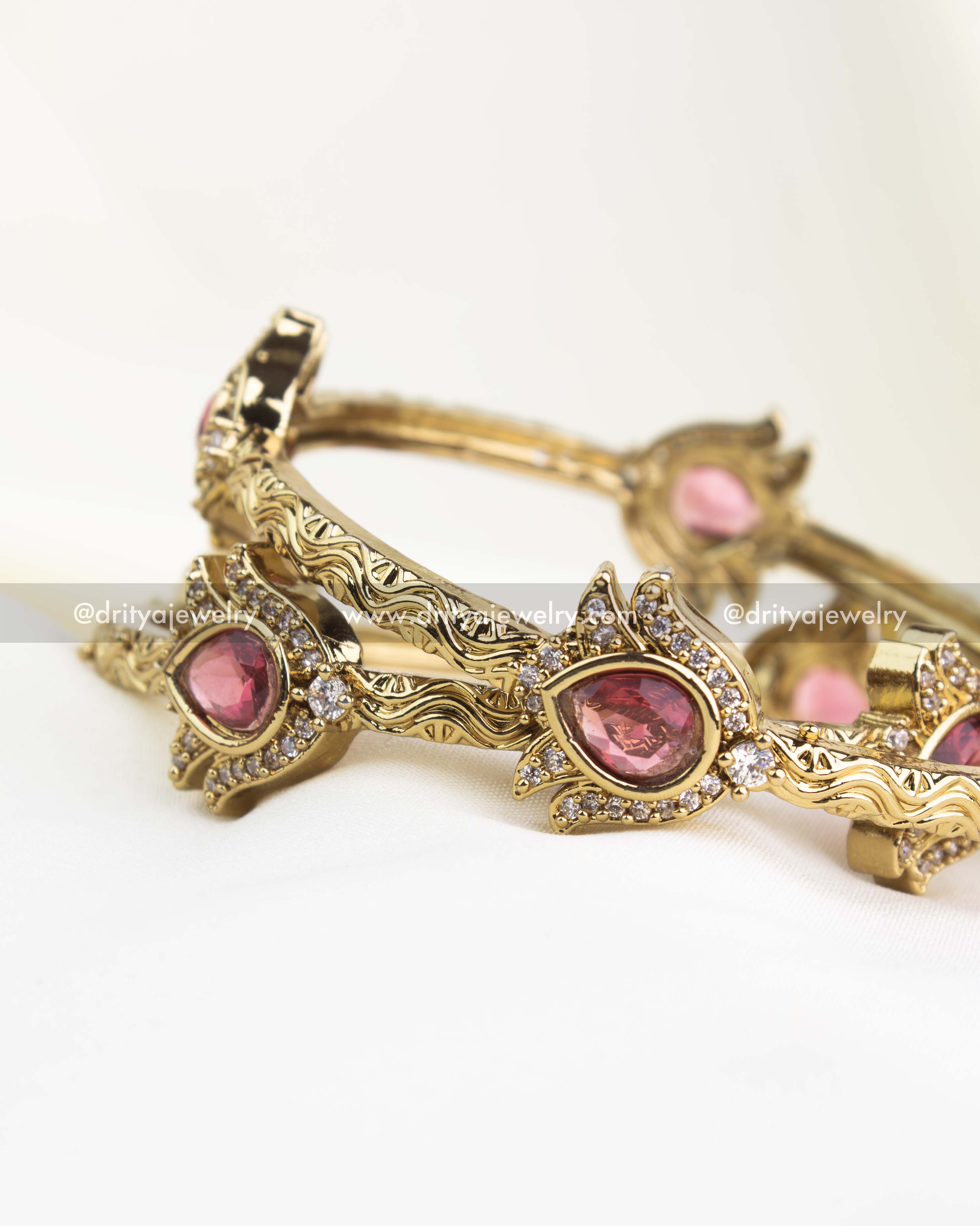 Detailed antique kada with ruby red pear stone, delicate carvings, and crystal accents.