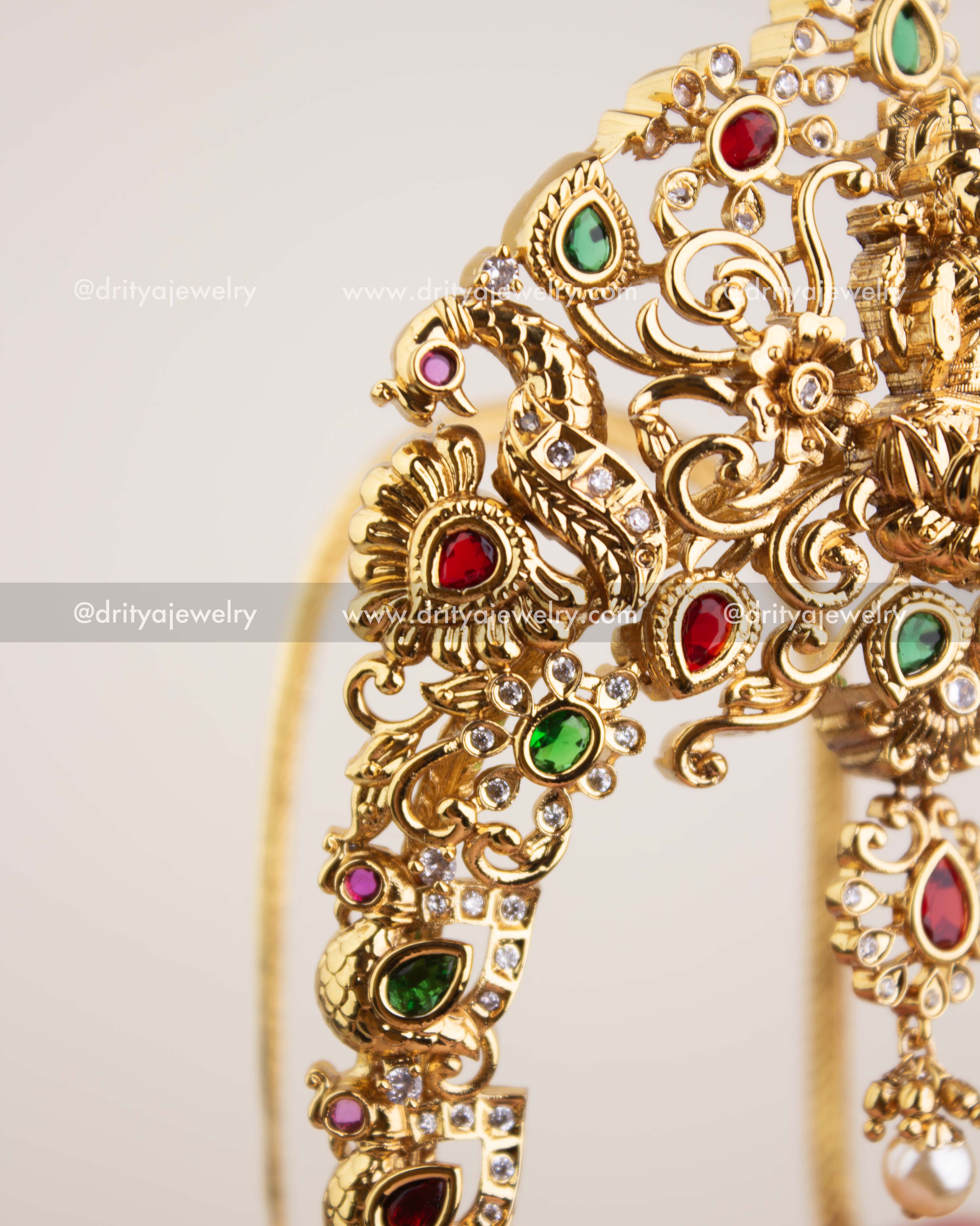Detailed view of peacock motif with ruby, emerald, and CZ stone embellishments on temple vanki.
