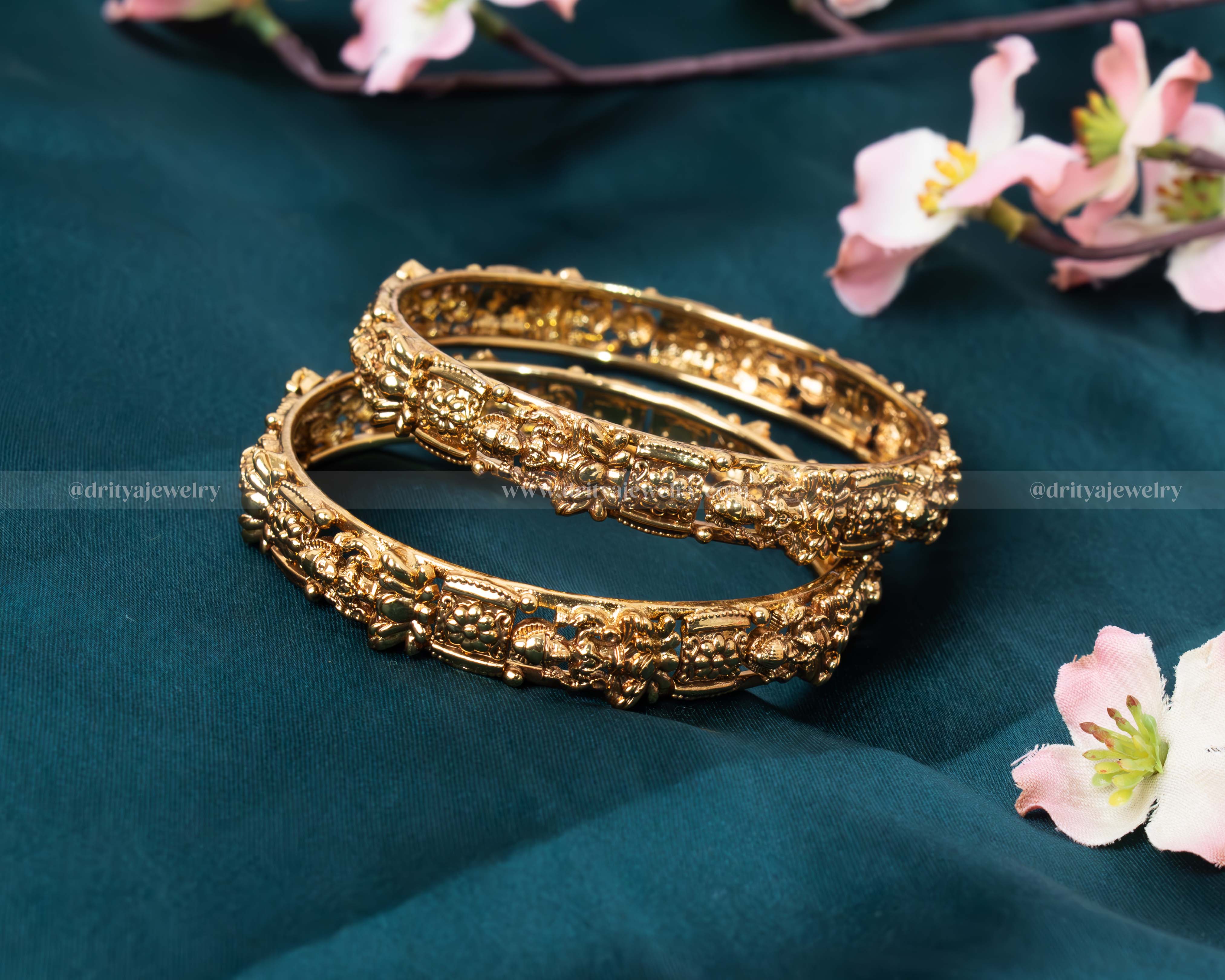 Close-up view of the Lakshmi Devi Temple Bangle showing the intricate traditional motifs and gold finish.