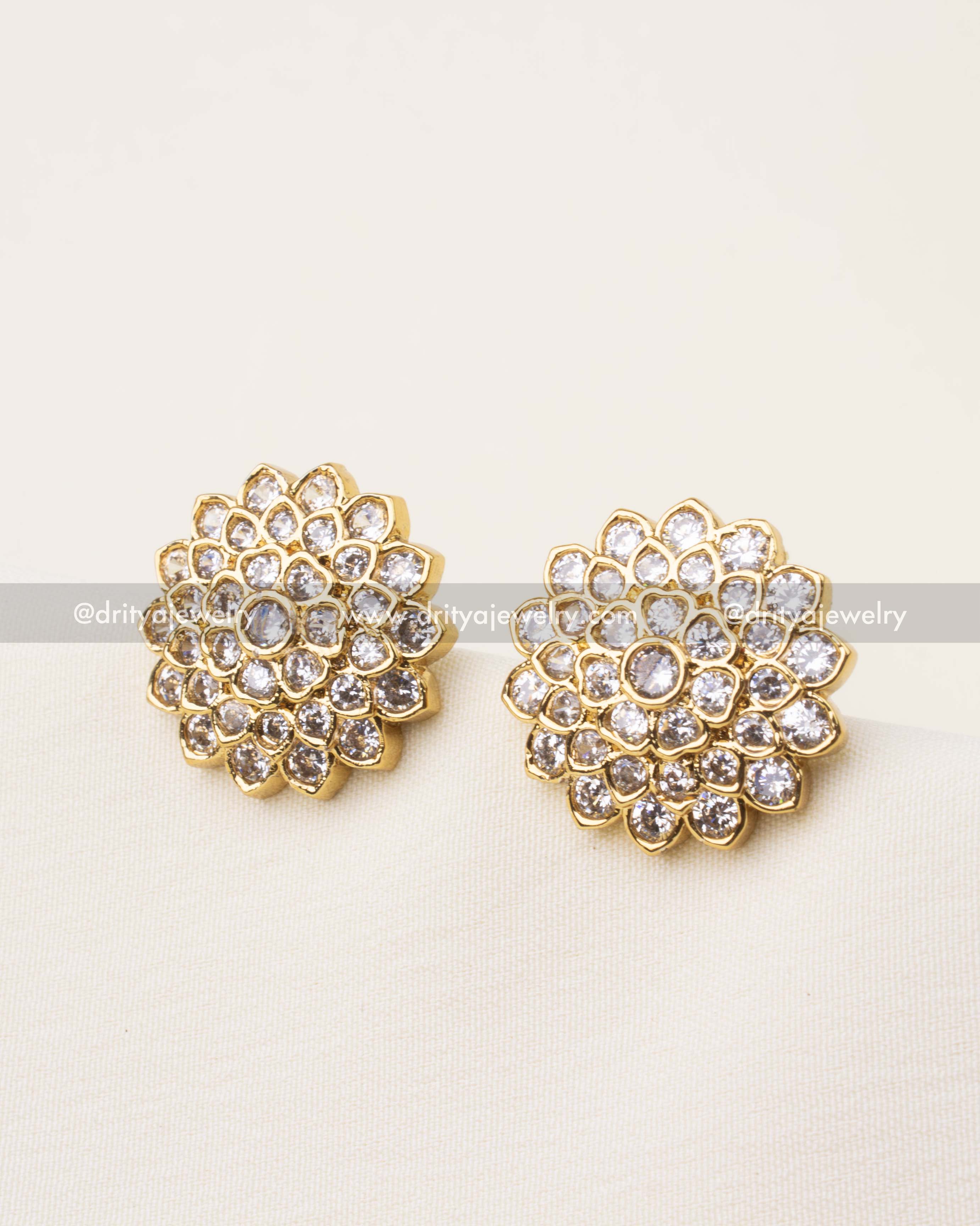 Elegant diamond-look floral stud earrings with multiple layers of stones and gold finish.