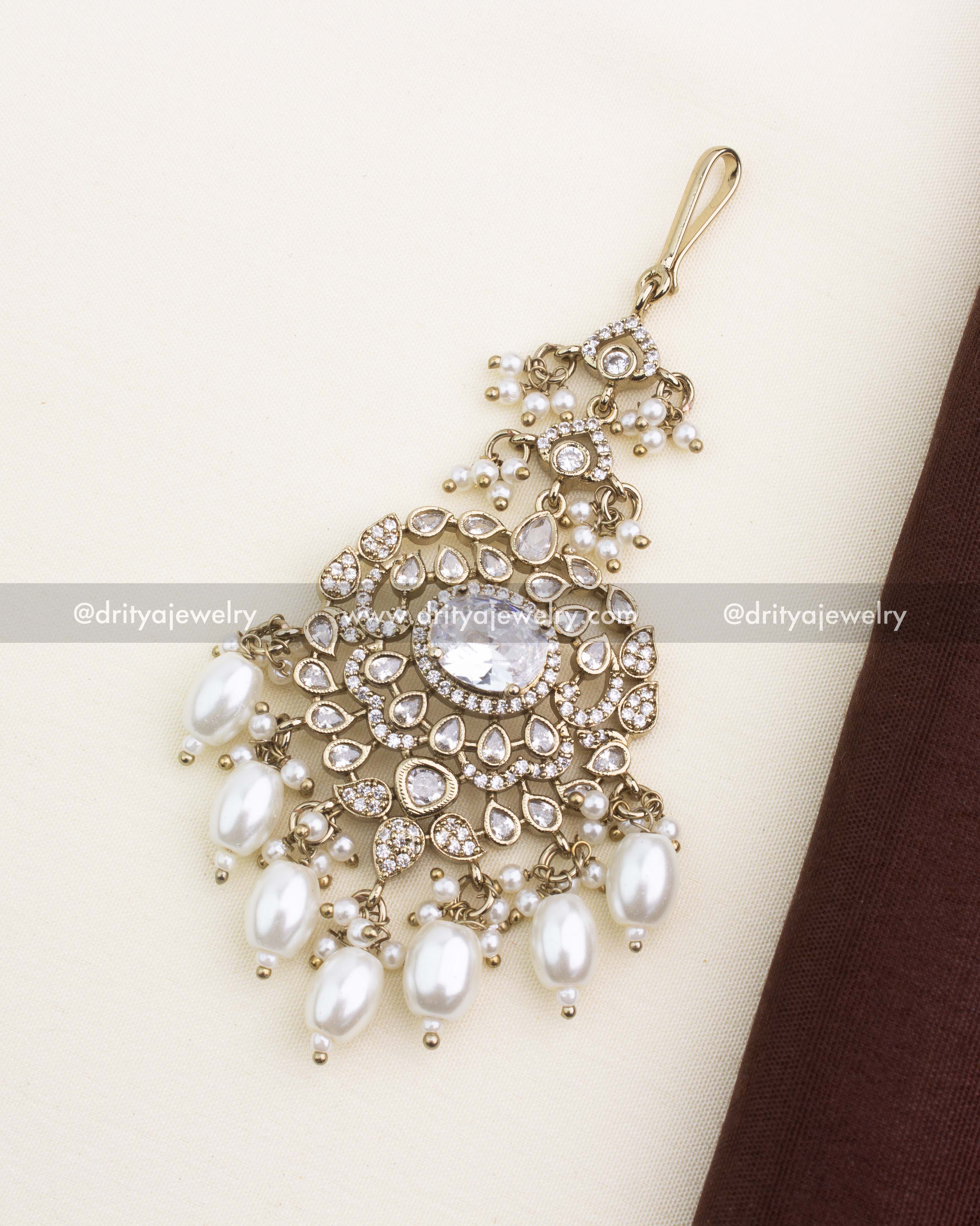 Victorian-style white stone maang tikka with AD clusters, pearl drops, and antique gold finish.