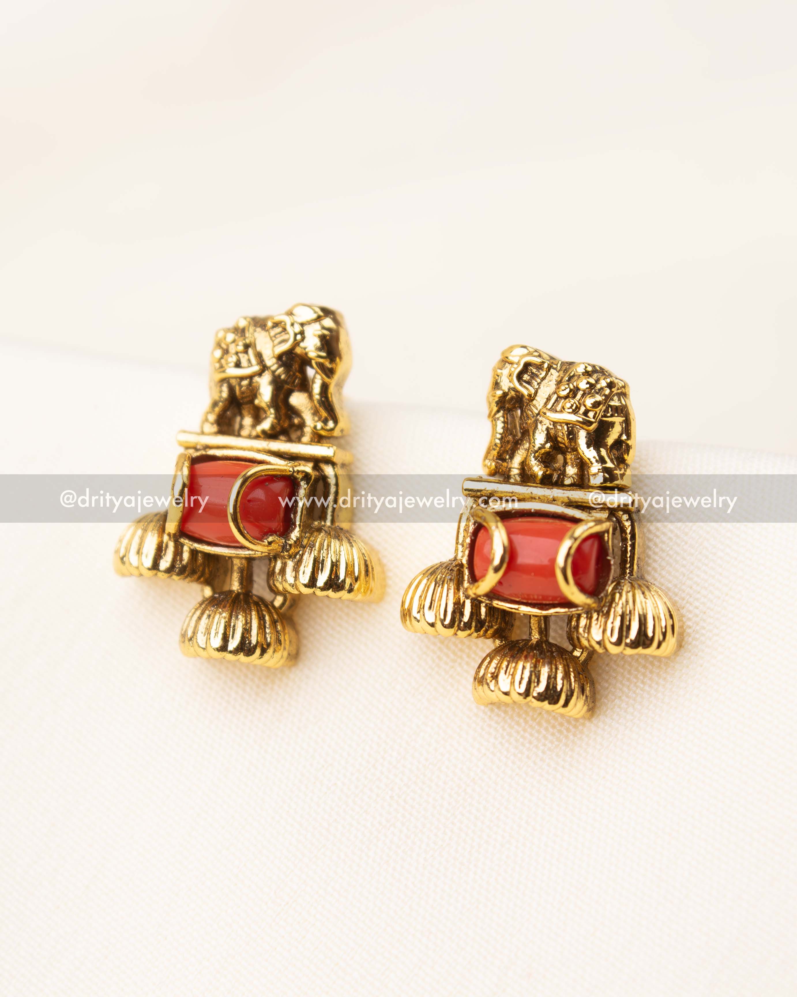 Stud earrings with elephant detailing and red coral bead accents in antique gold finish.