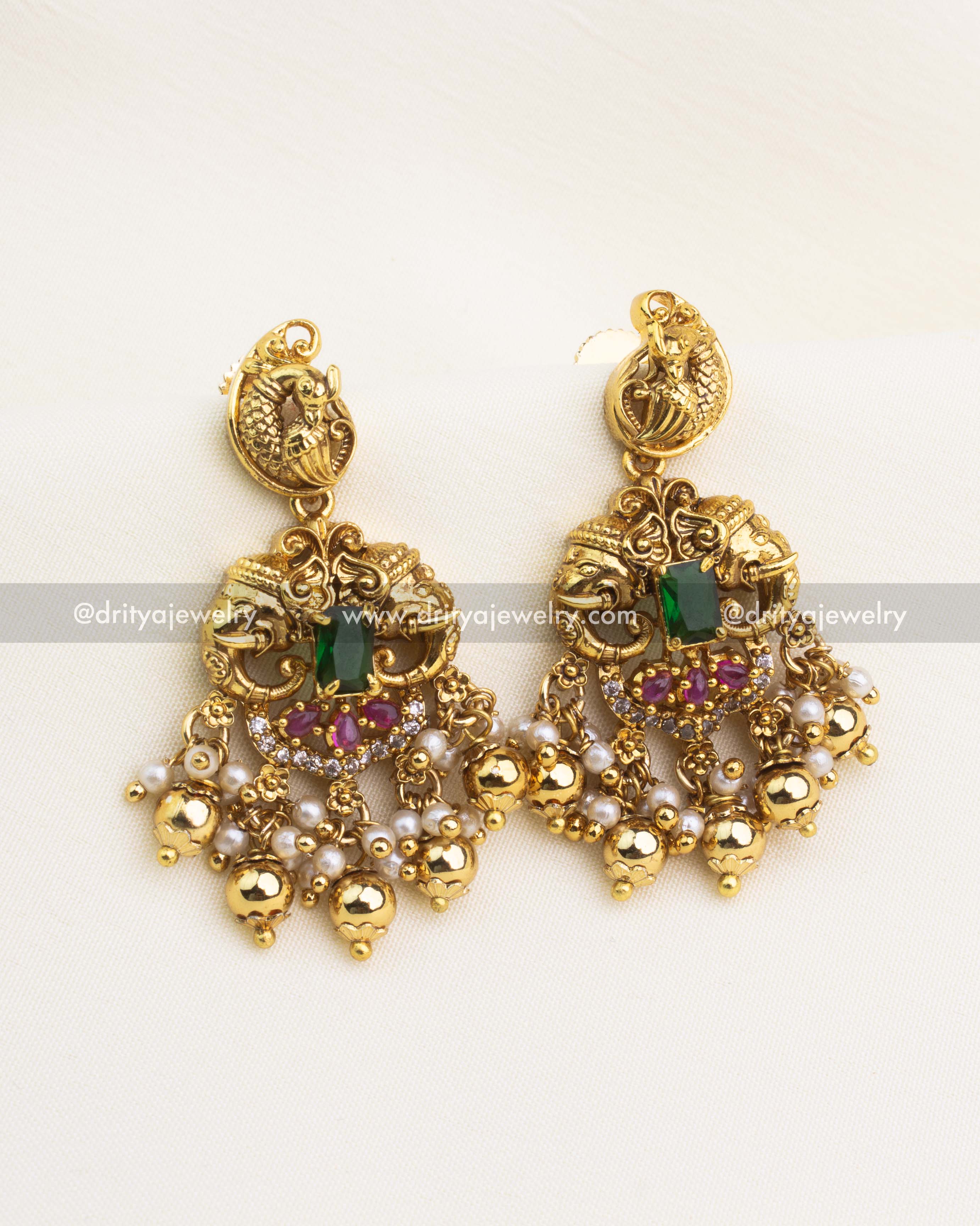 Matching earrings with peacock design, gold bead clusters, and emerald stone centerpiece.