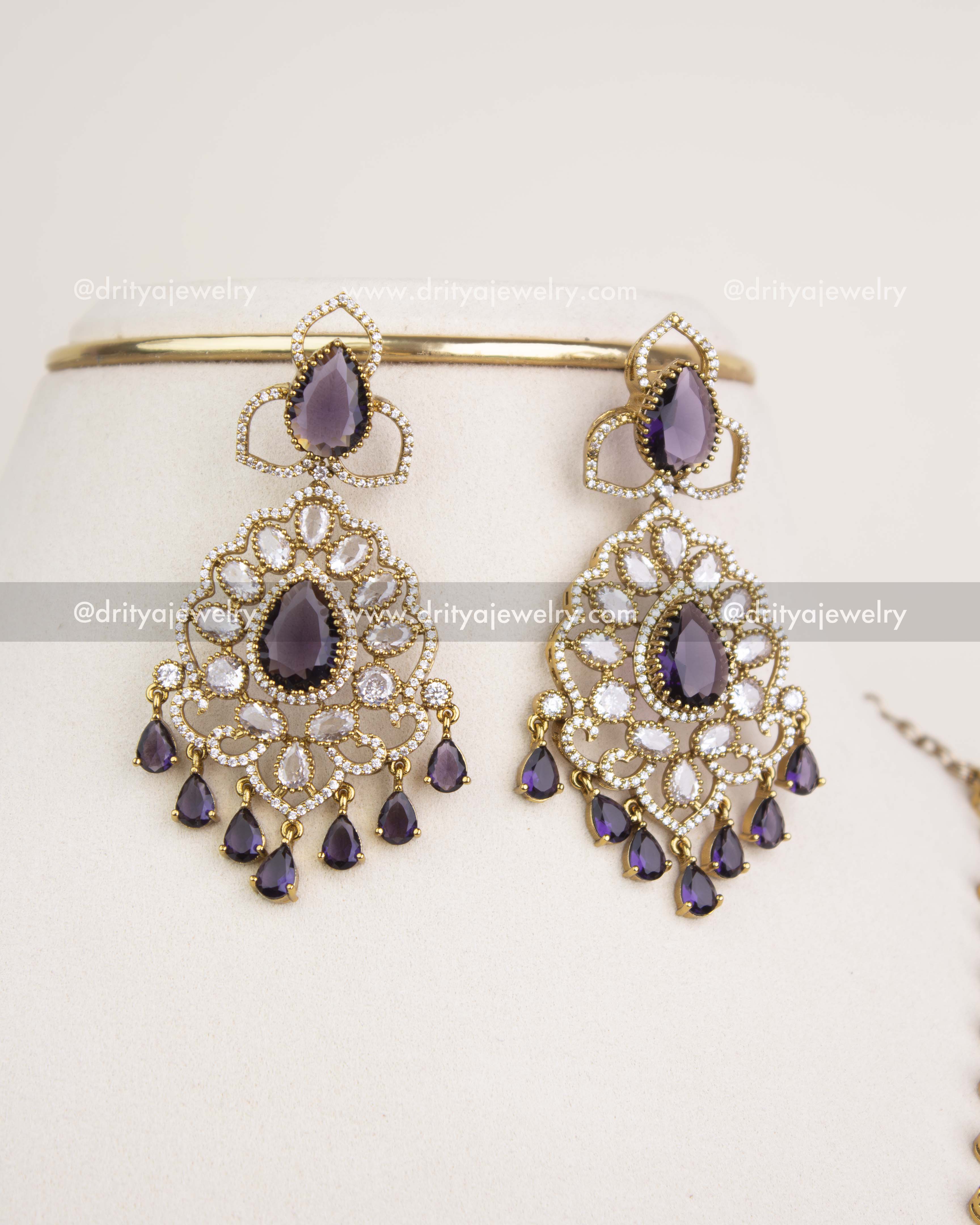 Big-size matching dangler earrings with purple teardrop stones and CZ clusters in Victorian finish.