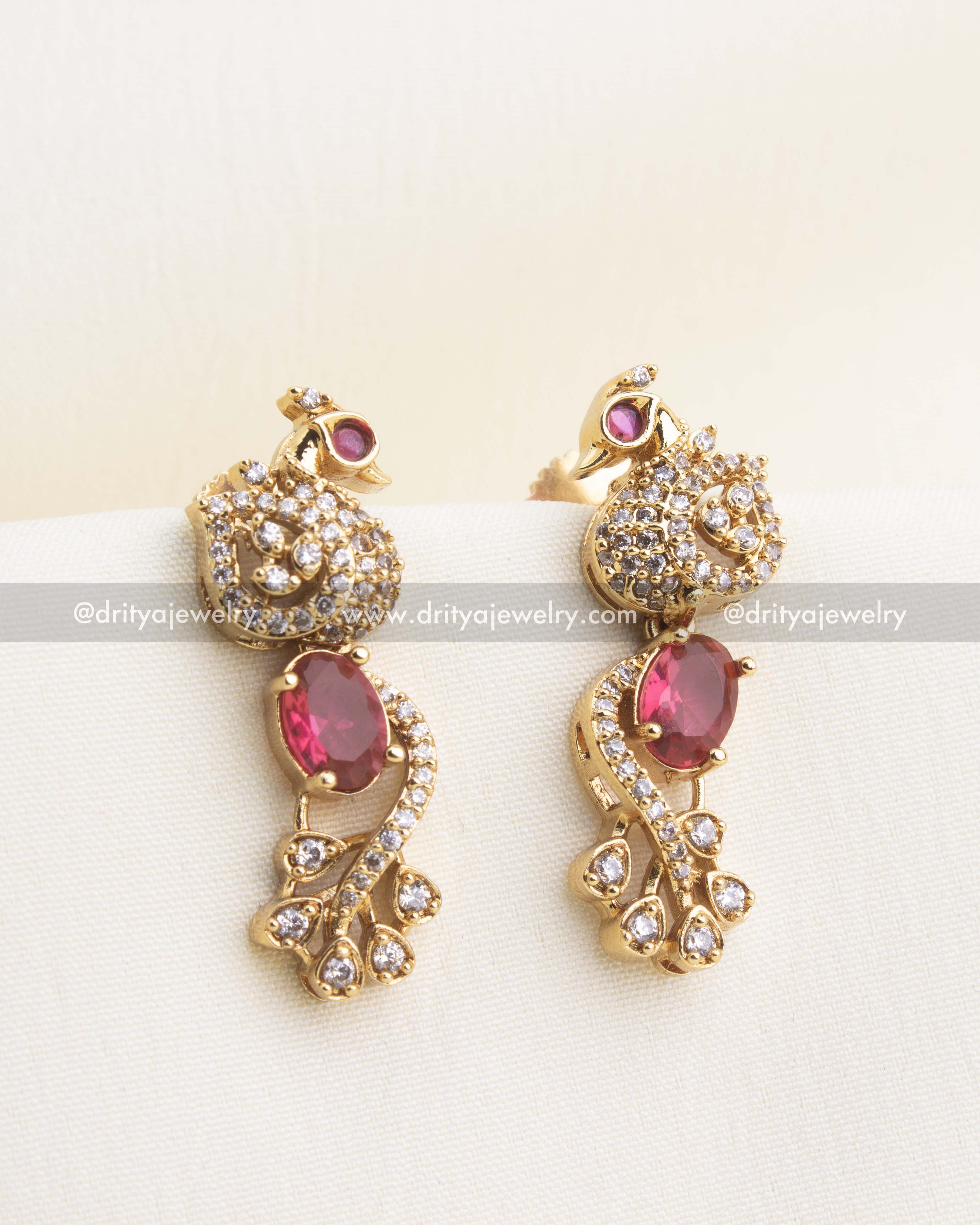 Gold-plated earrings with ruby CZ stones and peacock-shaped tops.
