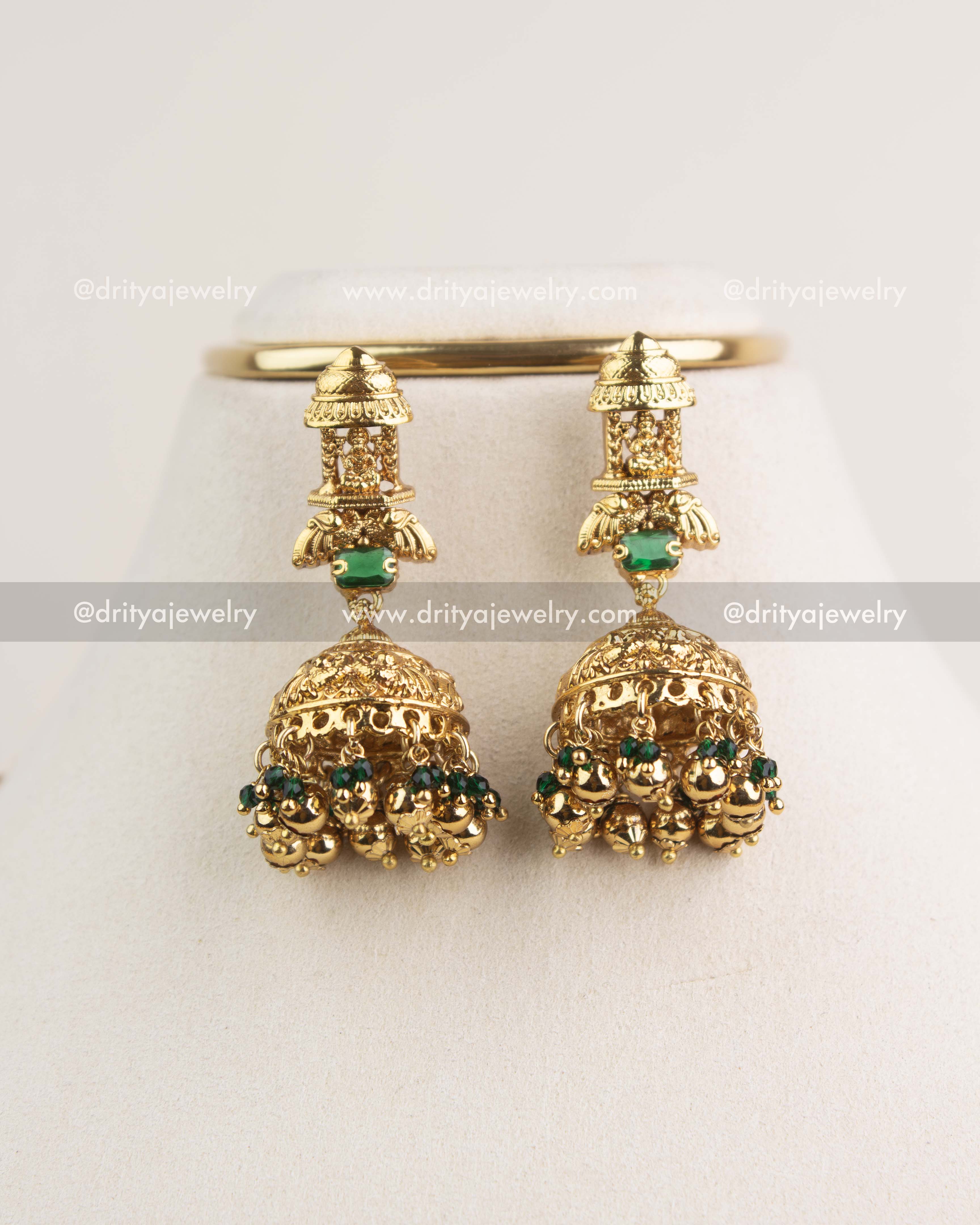 Pair of antique Nakshi jhumkas with green stones and gold bead clusters.