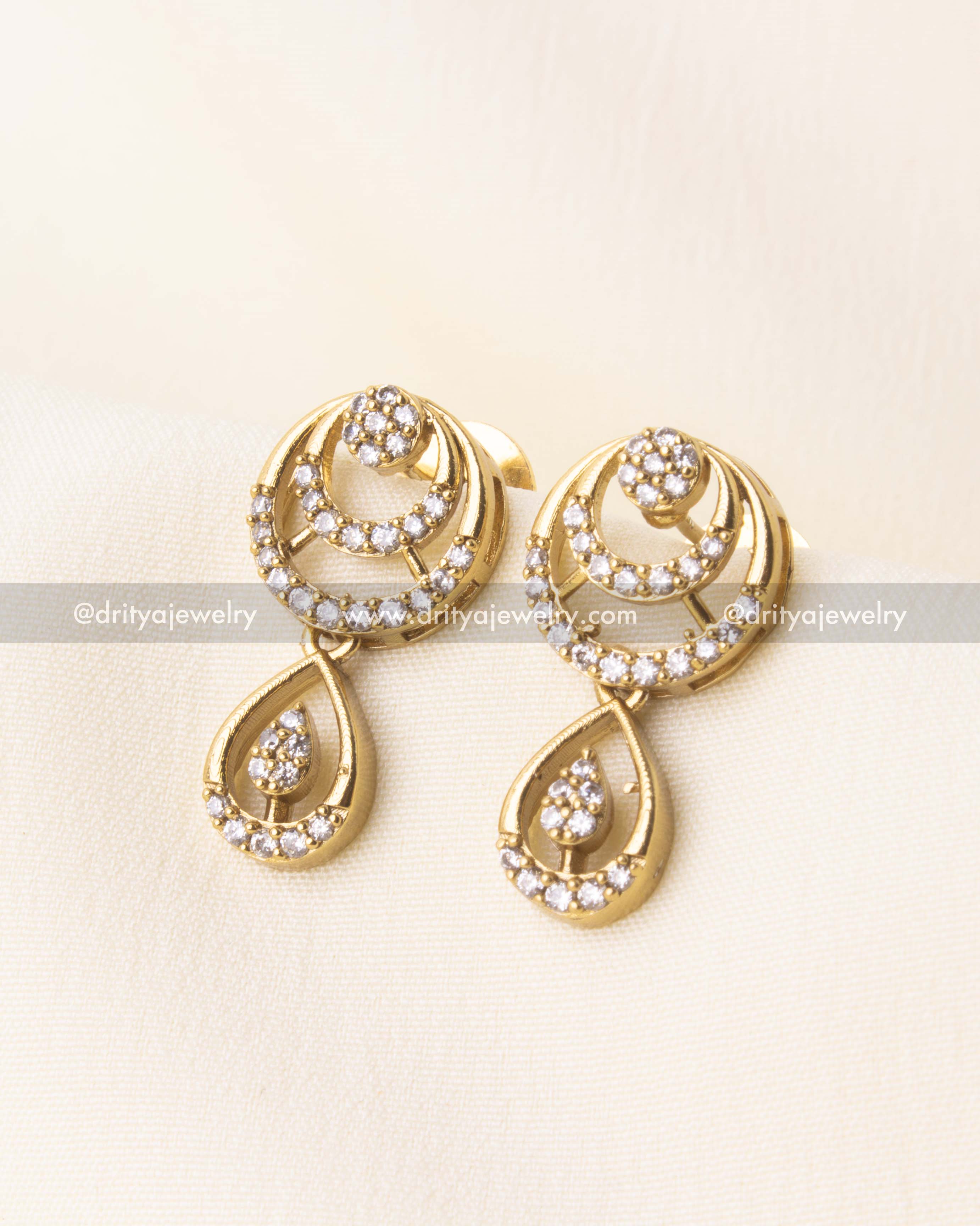 Matching CZ earrings with circular and tear-drop detailing in gold finish.