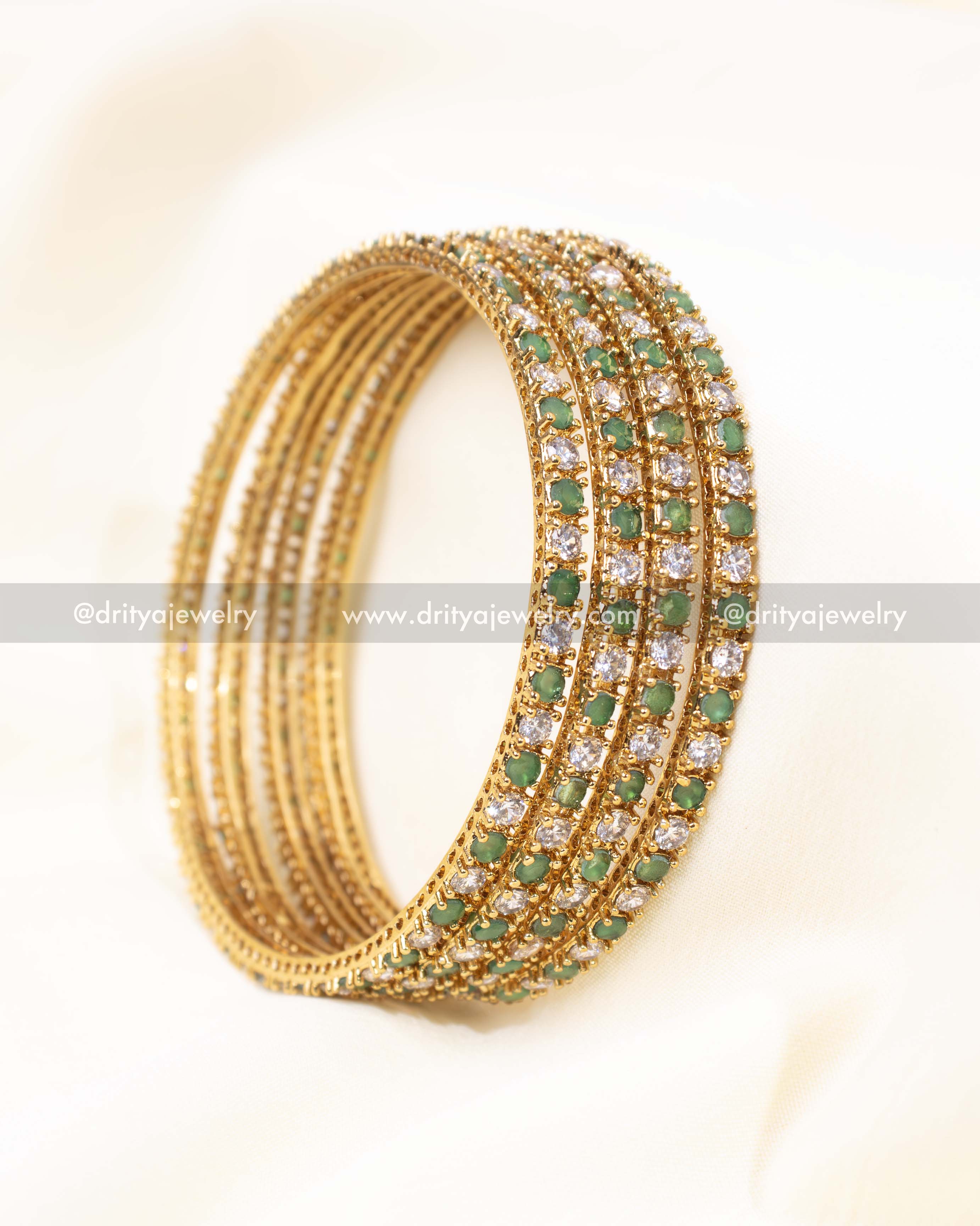 Detailed close-up view of green CZ bangles showcasing intricate stonework and a premium gold finish.