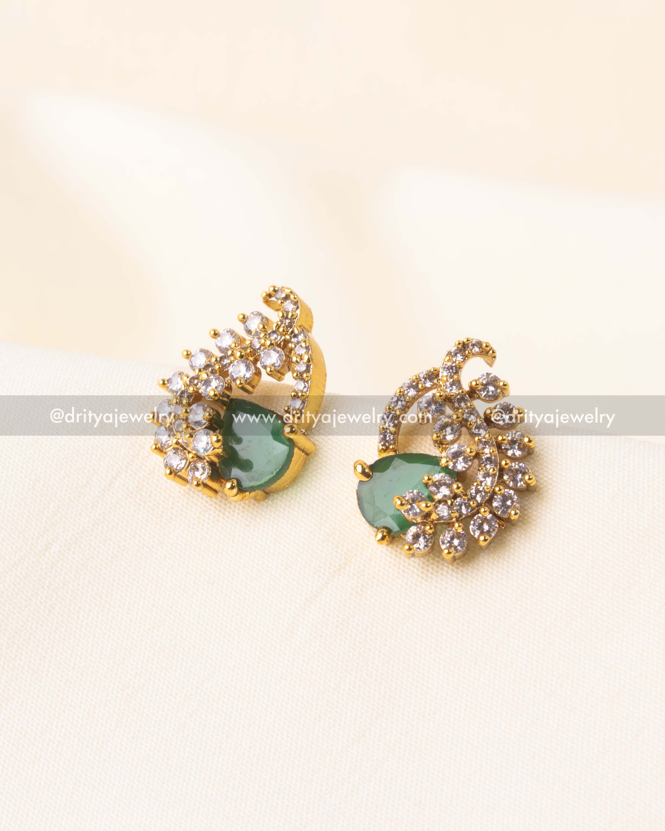 Gold-plated stud earrings with teardrop emerald green center stone and CZ swirl design.
