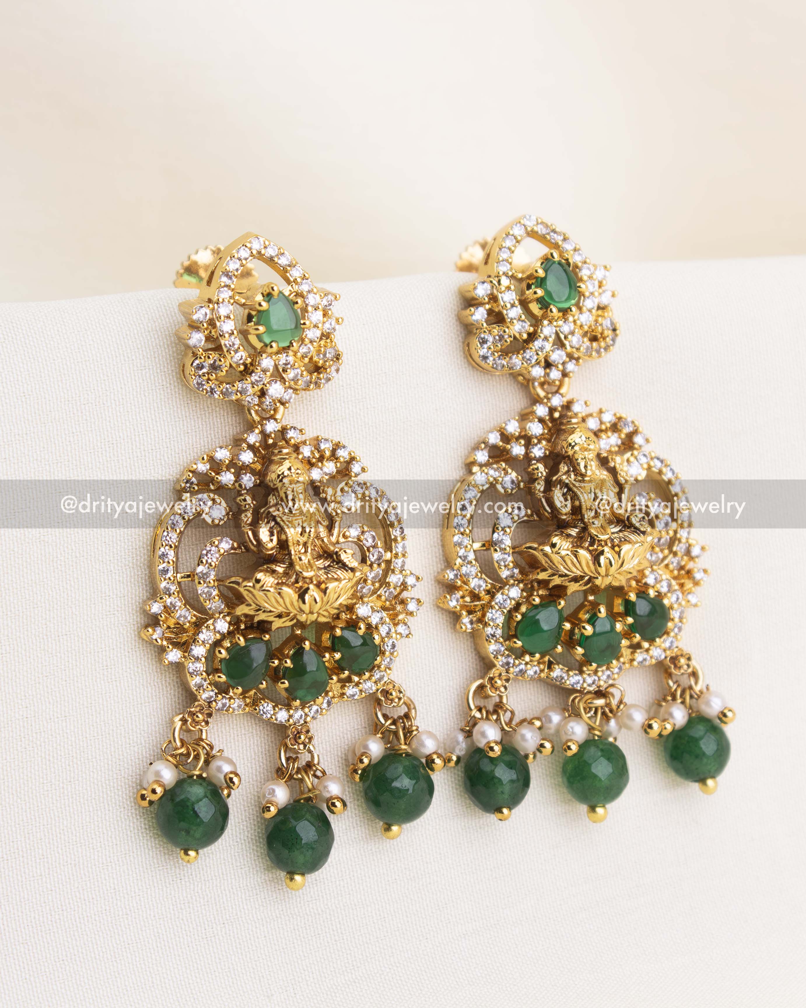 Premium temple earrings with Lakshmi idol, CZ stones, and emerald green drops.