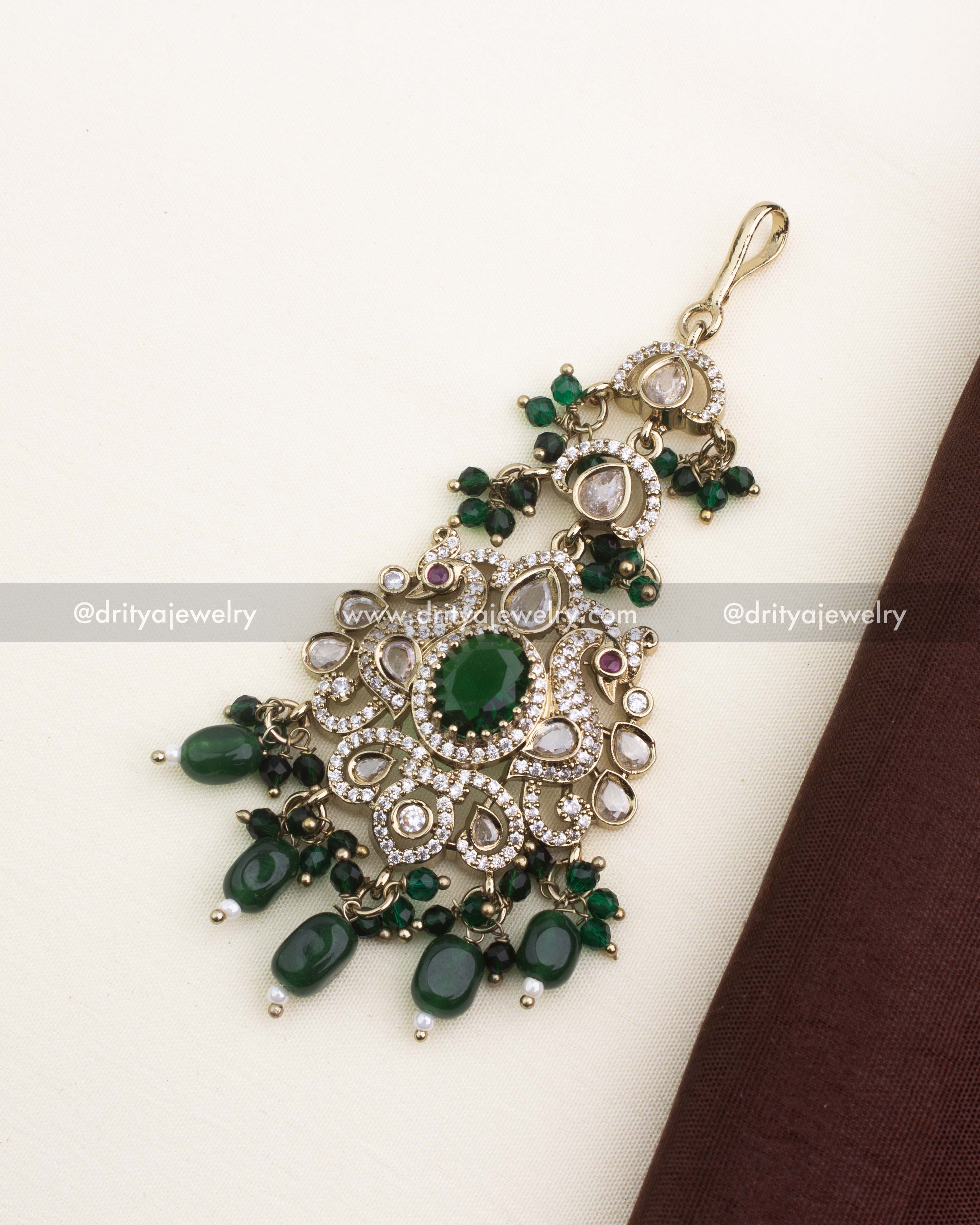 Victorian-style maang tikka with emerald green stones, kundan detailing, and green bead hangings