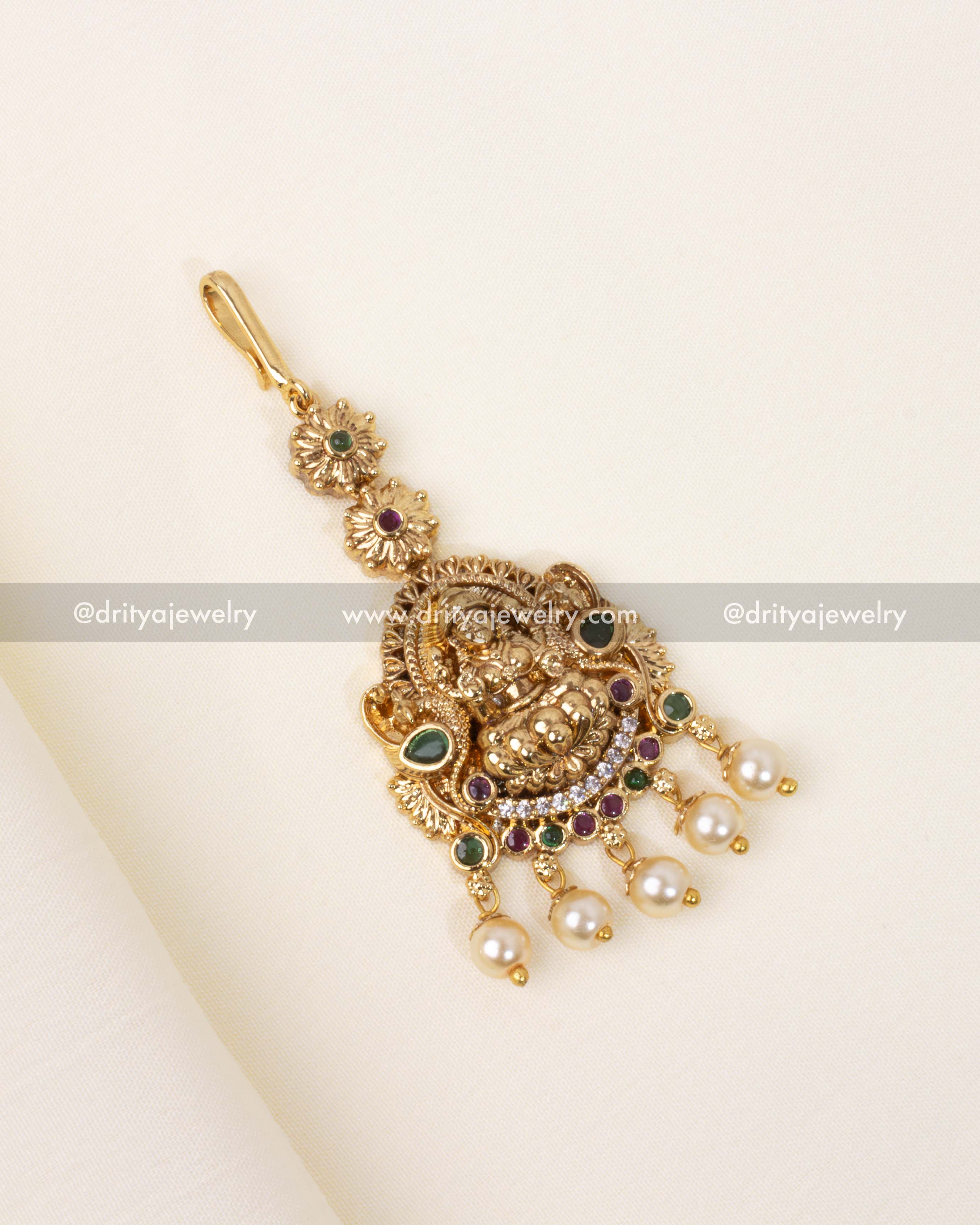 Traditional Nakshi Maang Tikka in antique gold polish with pearl and gemstone embellishments.