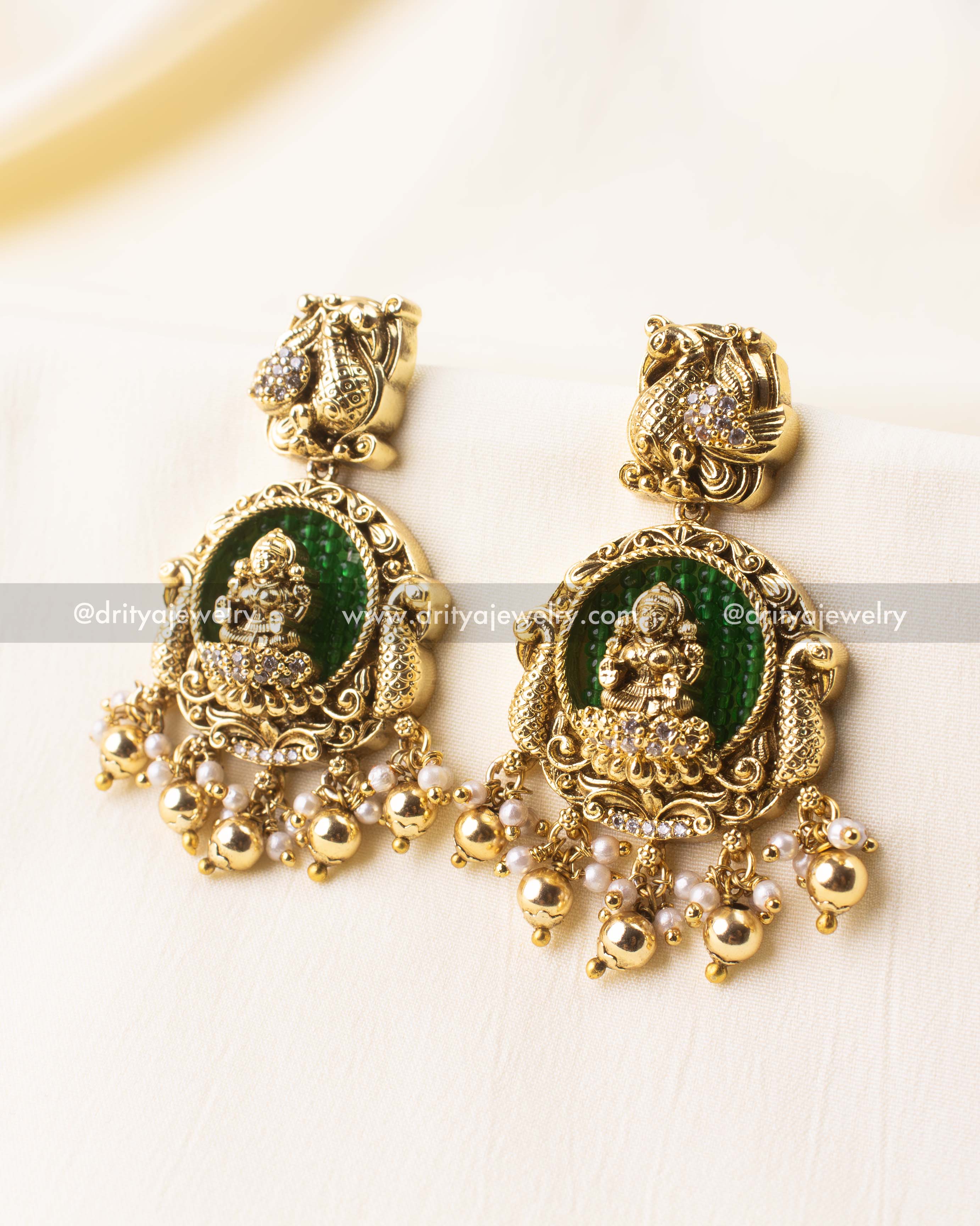 Close-up of divine earrings with Lakshmi motif and golden accents.