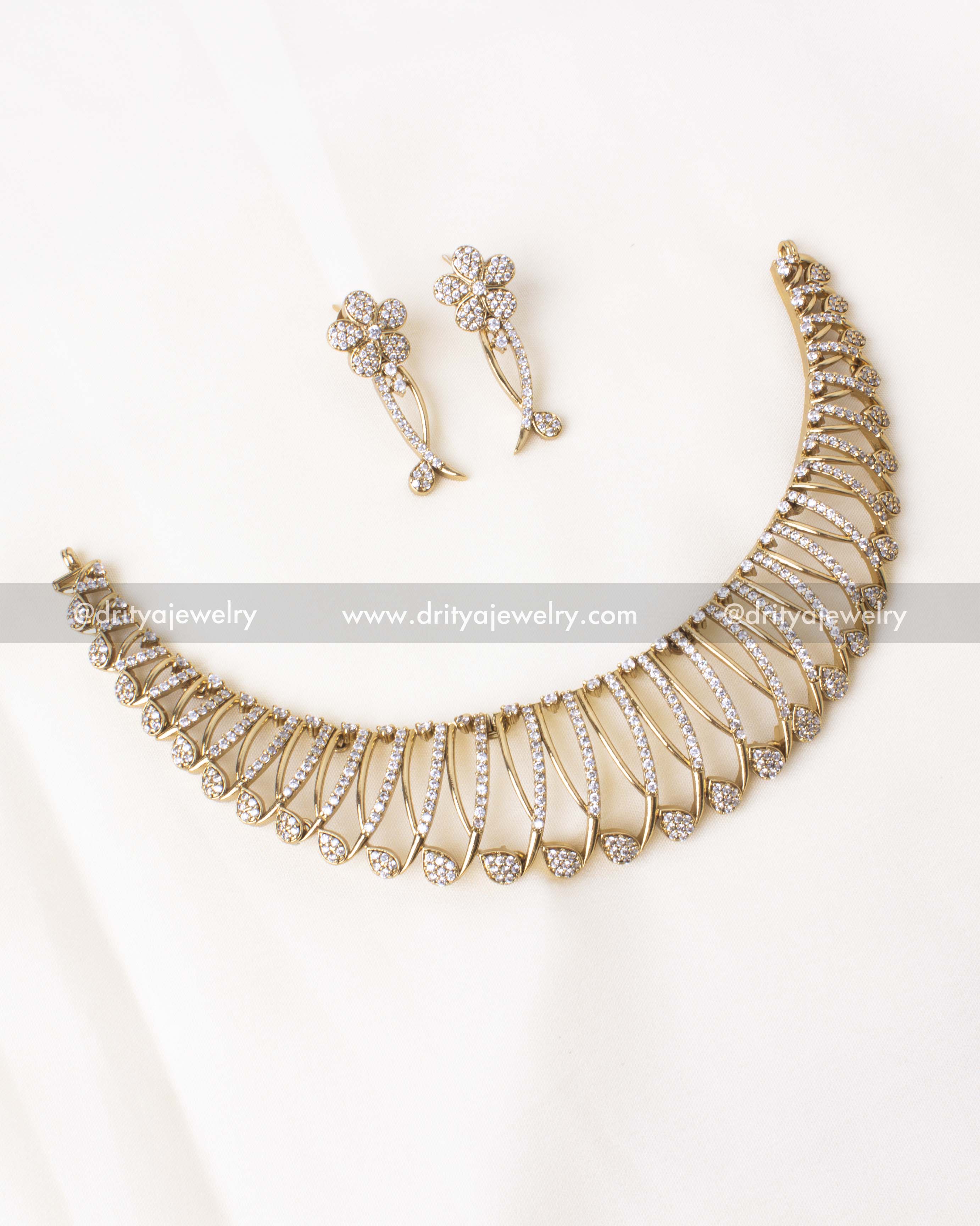 Elegant floral gold-plated necklace set with matching earrings featuring sparkling stones.