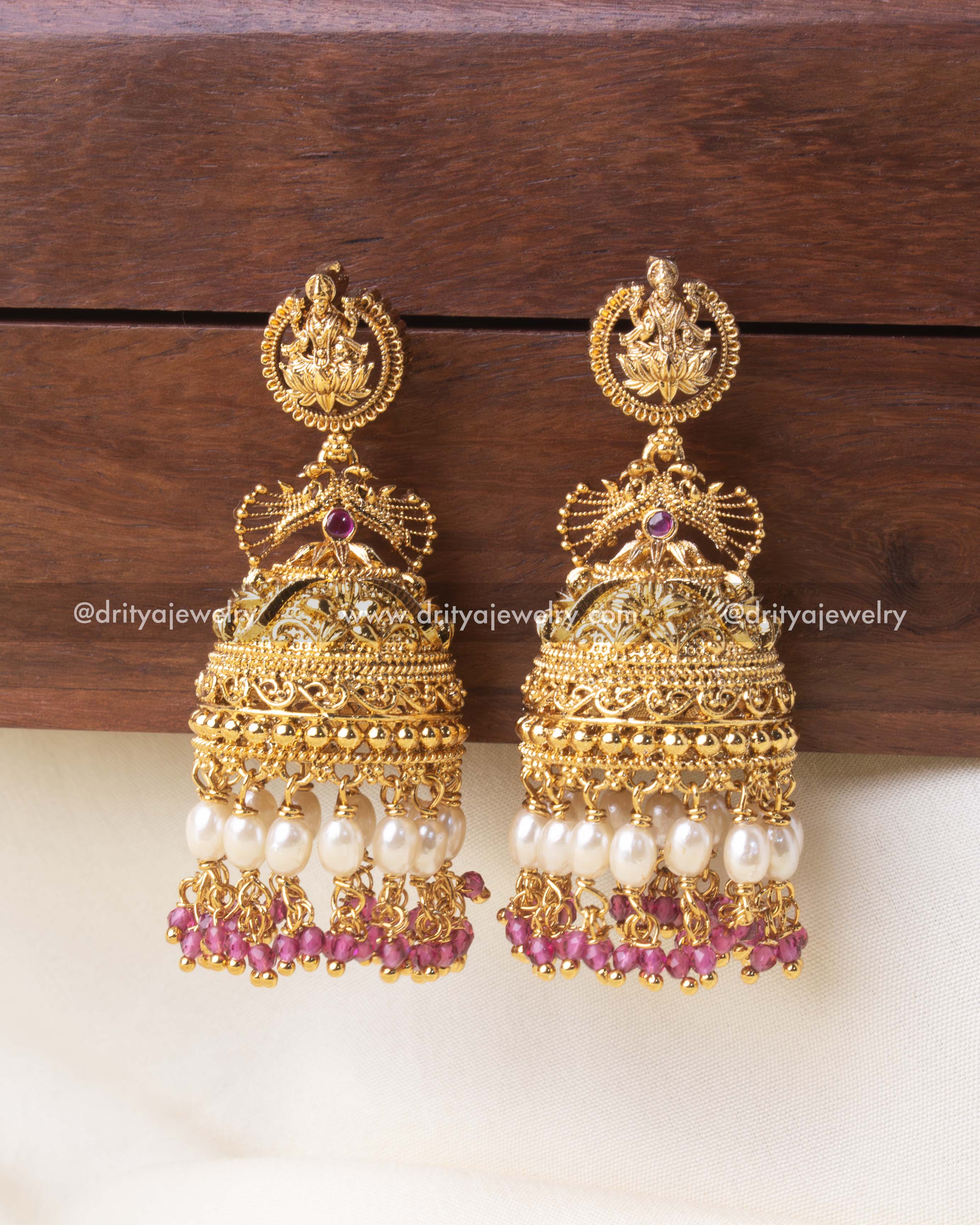 Exquisite temple Jhumka earrings with gold detailing, pearl drops, and pink crystal beads.