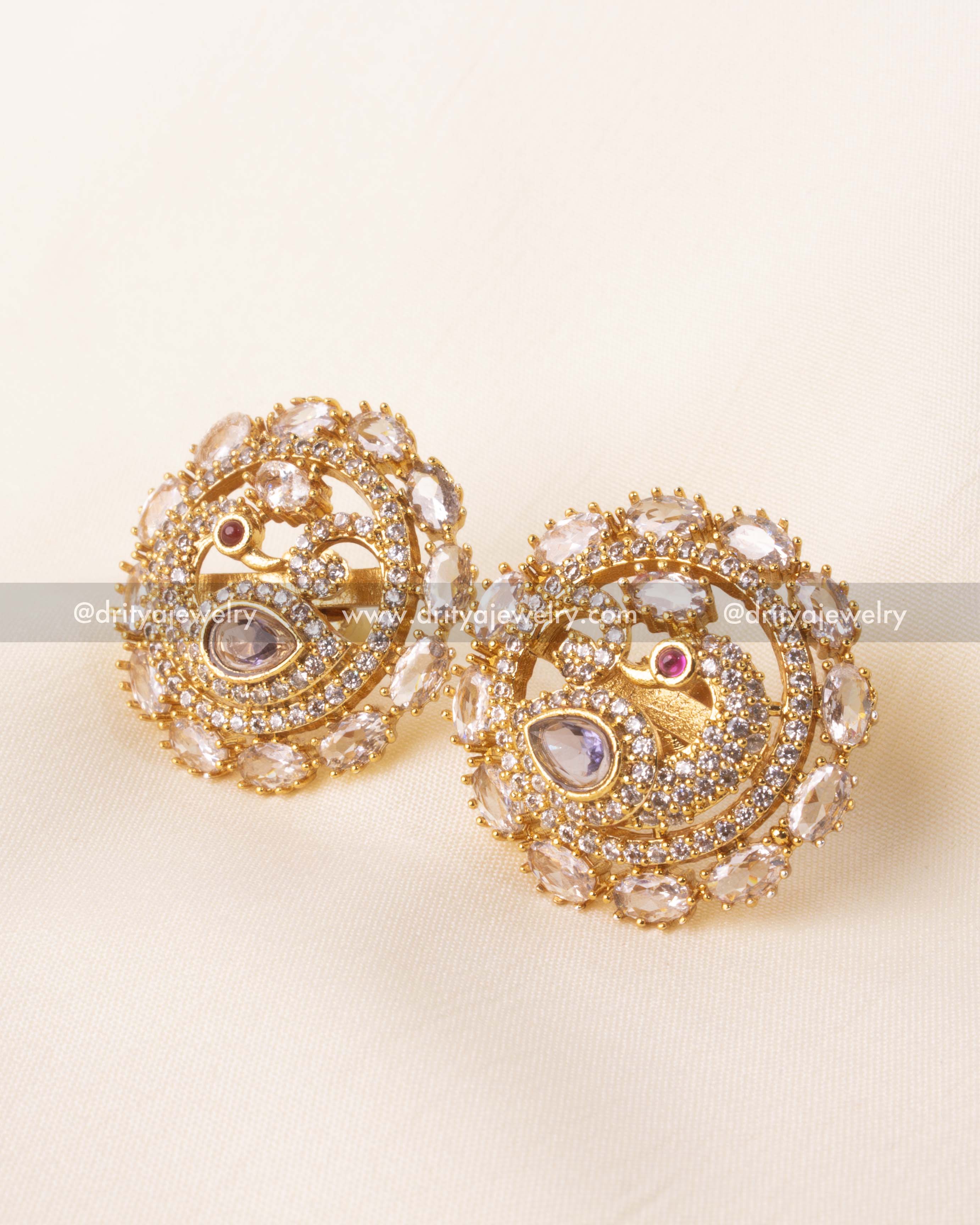 Elegant circular gold-plated stud earrings with a peacock design and kundan embellishments.