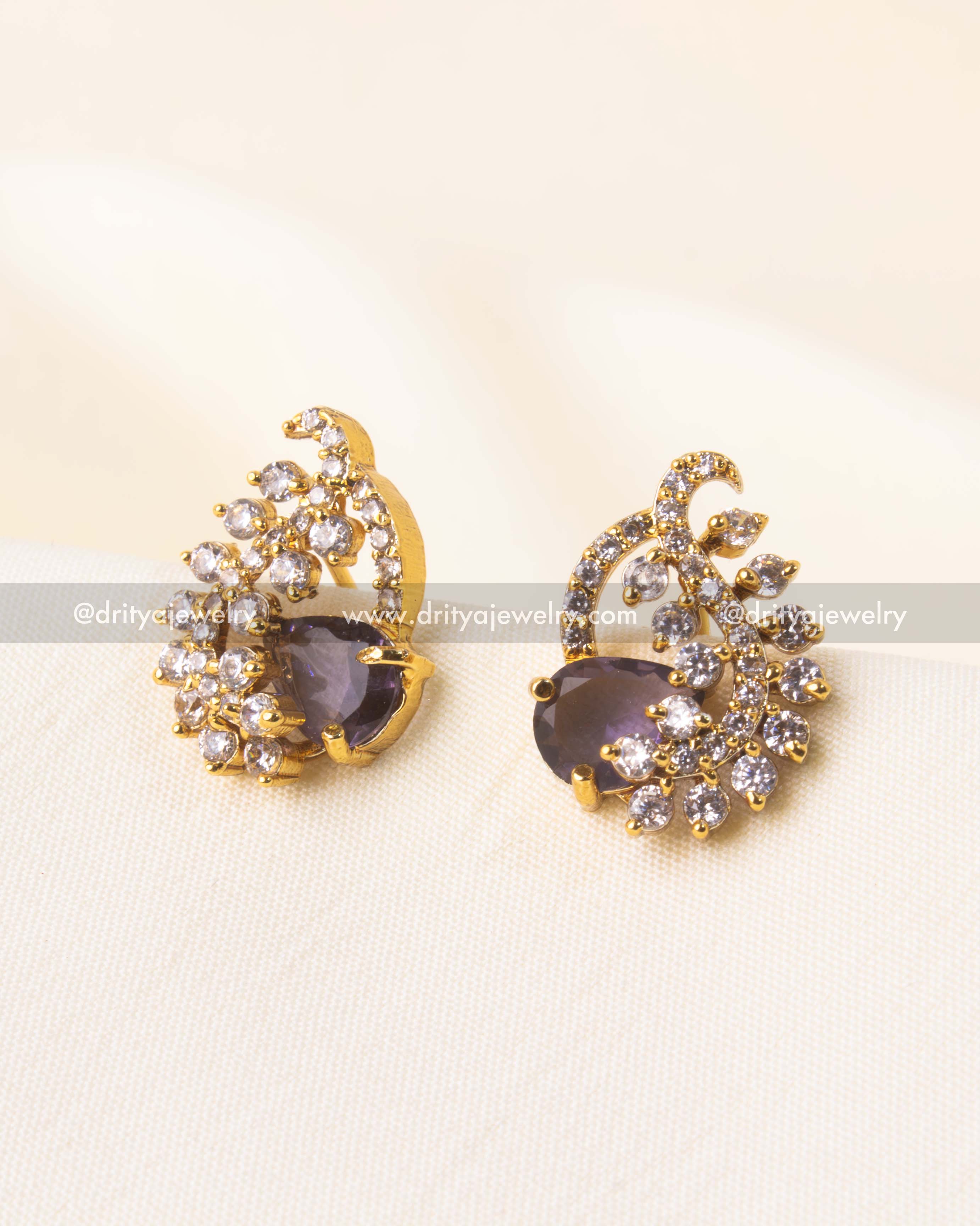 Purple stud earrings with gold-plated swirl design and CZ stone detailing.
