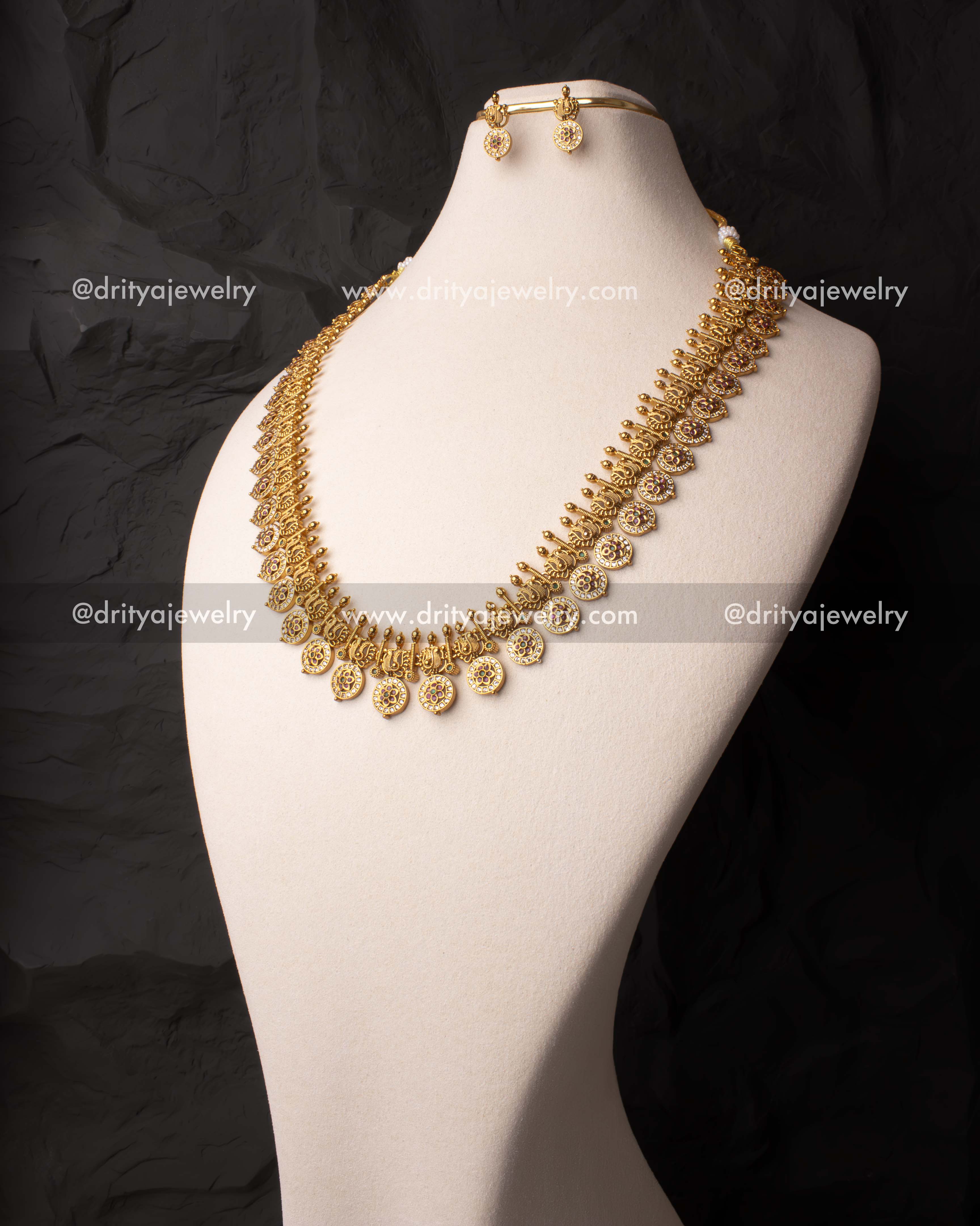 Heritage-inspired long necklace with intricate peacock carvings, gold finish, and pink-green stone embellishments.