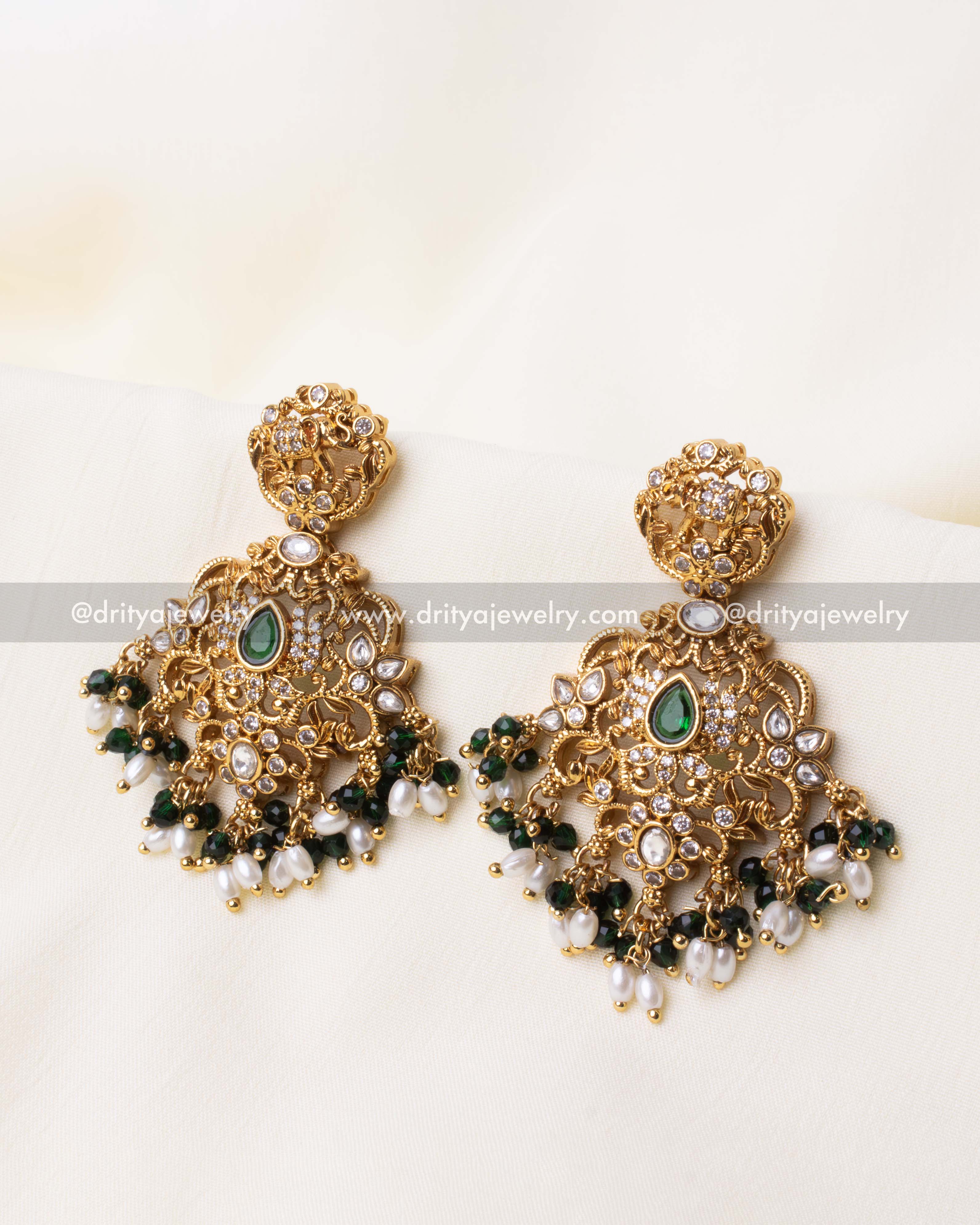 Elegant gold-plated dangler earrings with green gemstones, intricate elephant motif, and pearl bead accents.