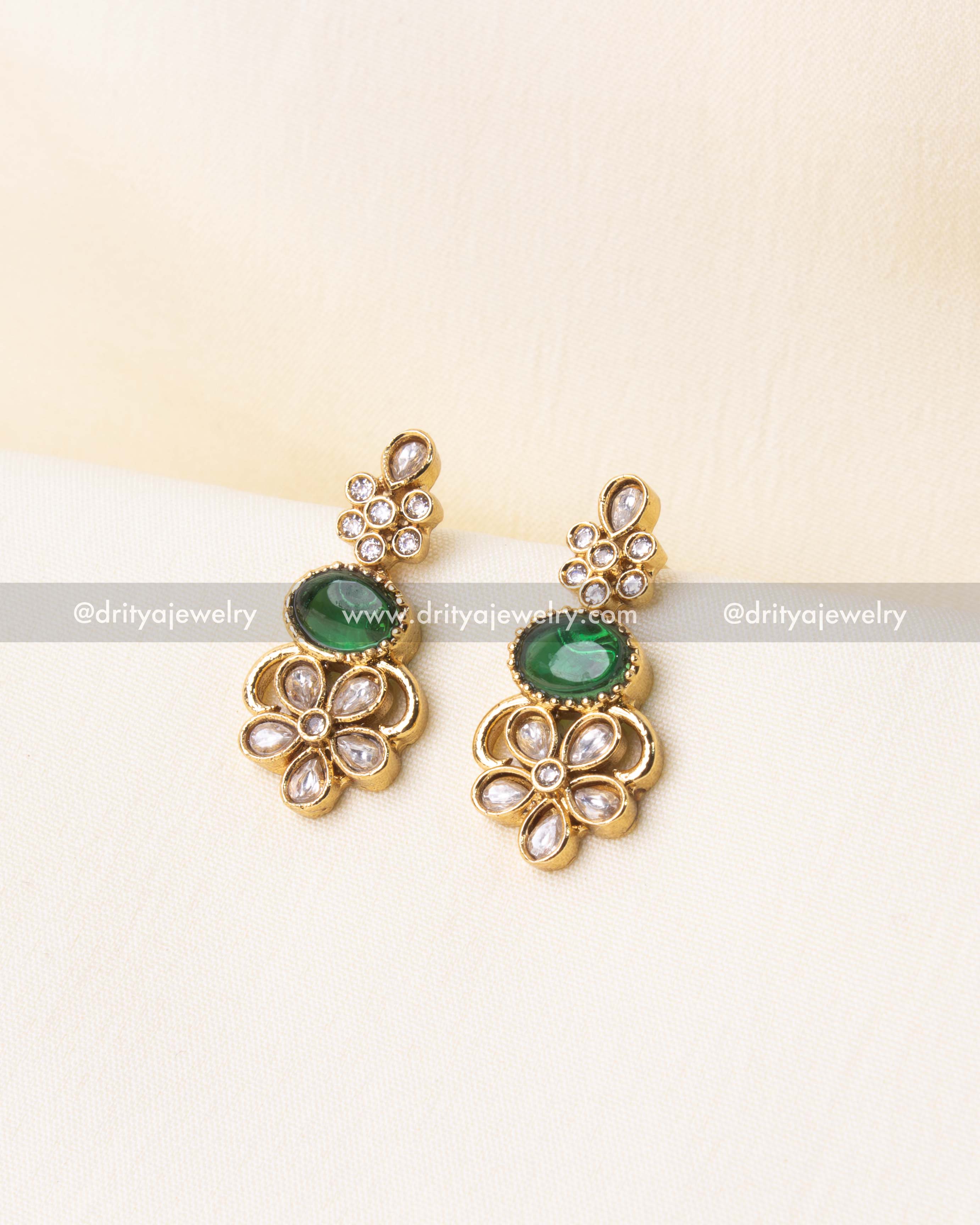 Matching earrings with green gemstones and floral patterns.