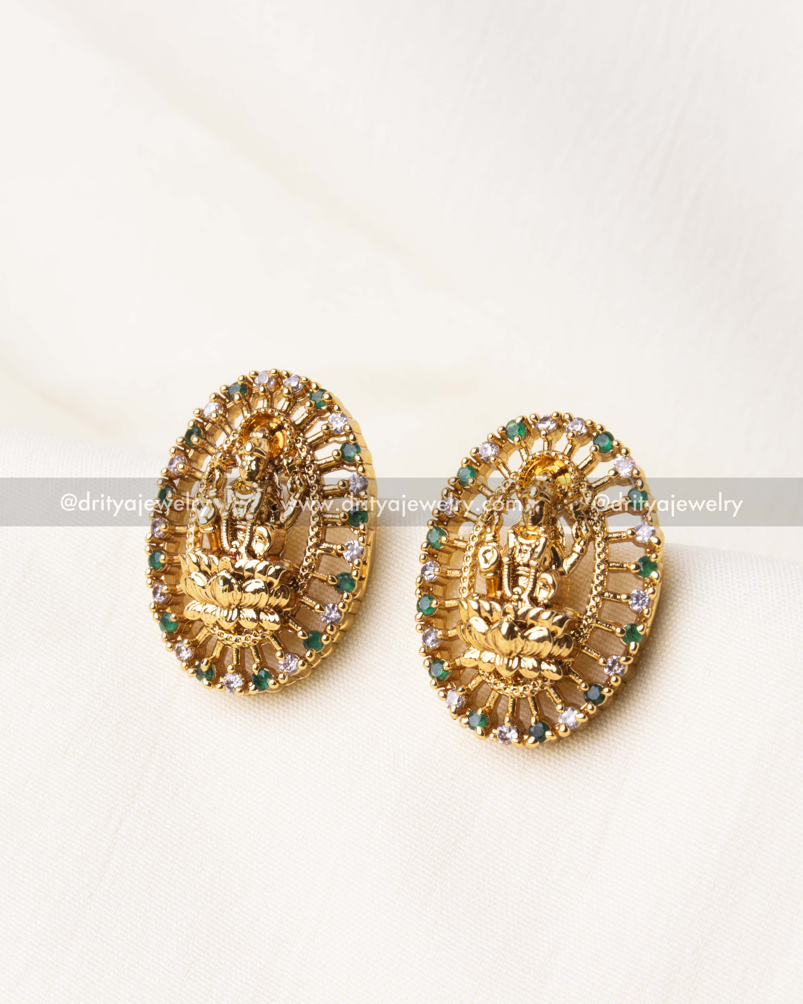 Antique gold-polished Nakshi stud earrings featuring green CZ stones and intricate Lakshmi Devi design.