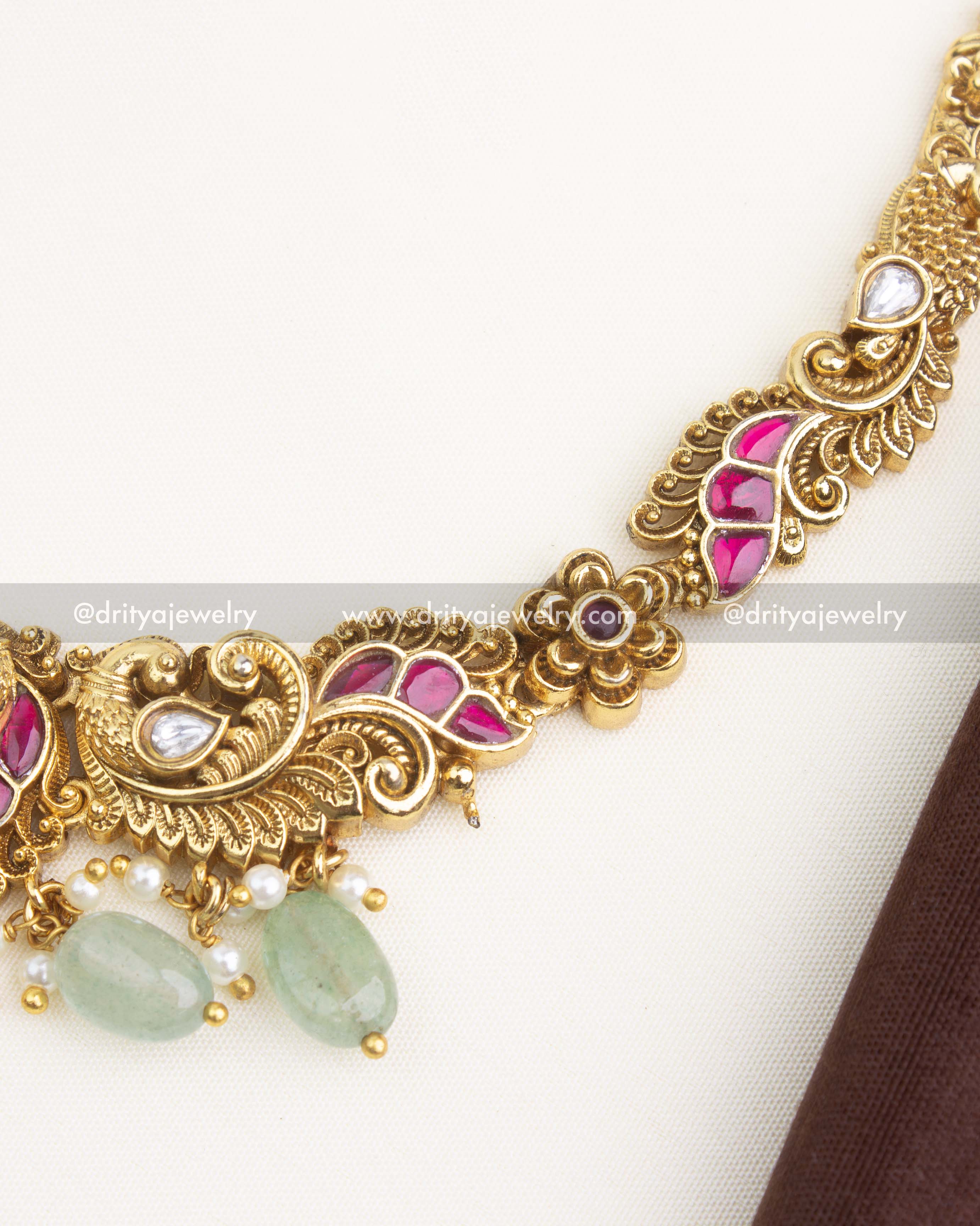 Close-up of necklace chain featuring pink kemp inlay, polki kundan stones, and carved antique motifs