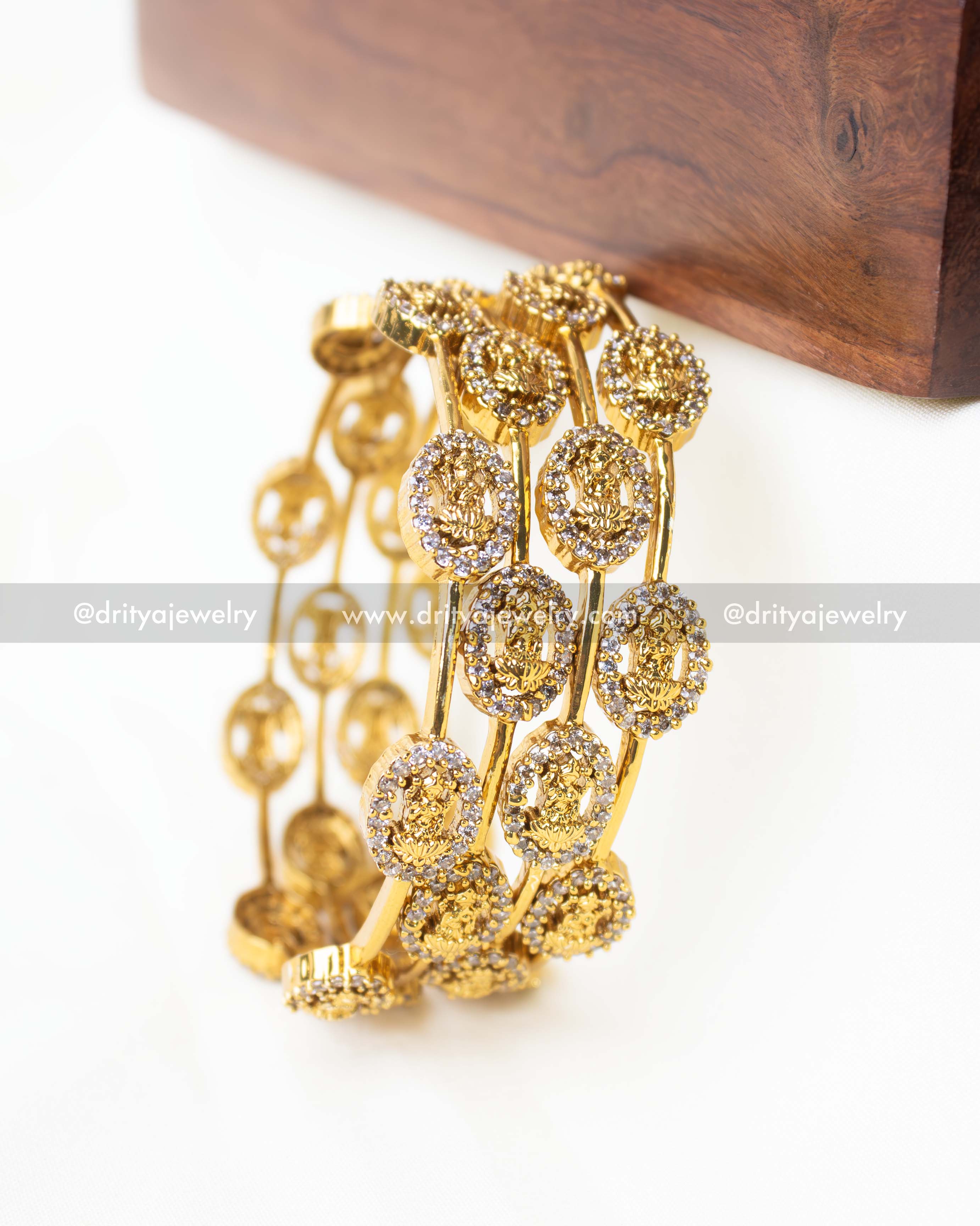 Premium gold-plated Lakshmi temple bangles with intricate motifs and white stone accents.