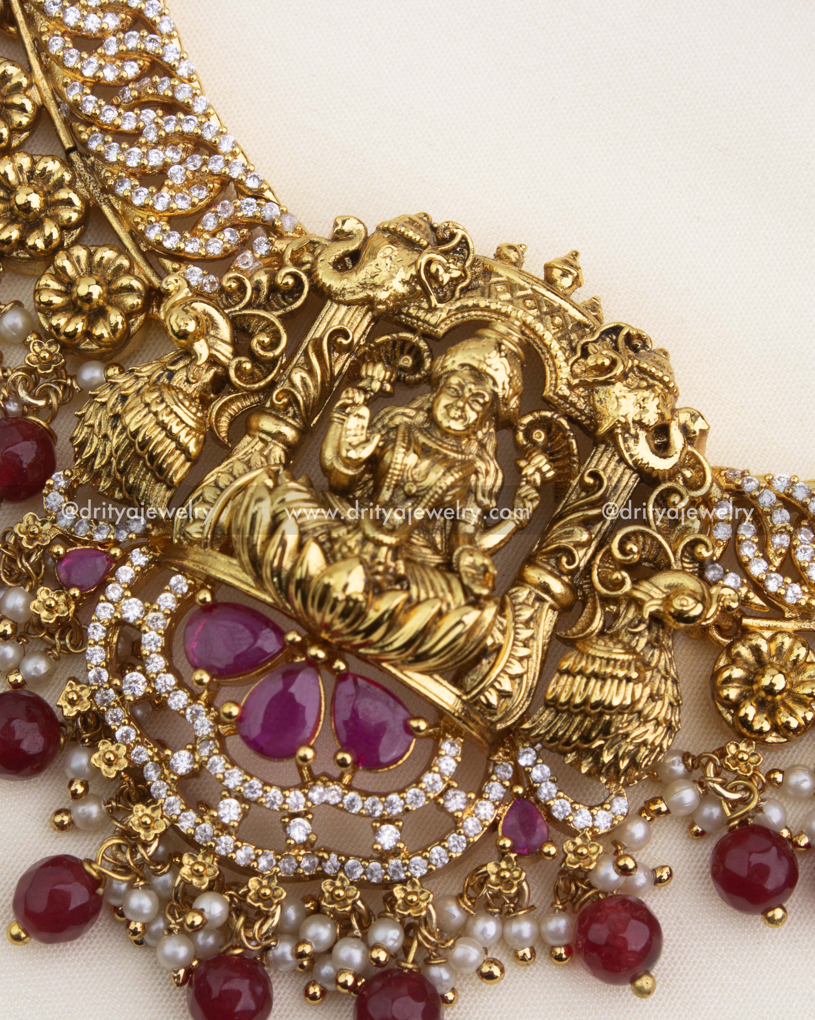 Detailed Lakshmi temple pendant with CZ jalebi design, ruby stones, and pearl–ruby hangings.