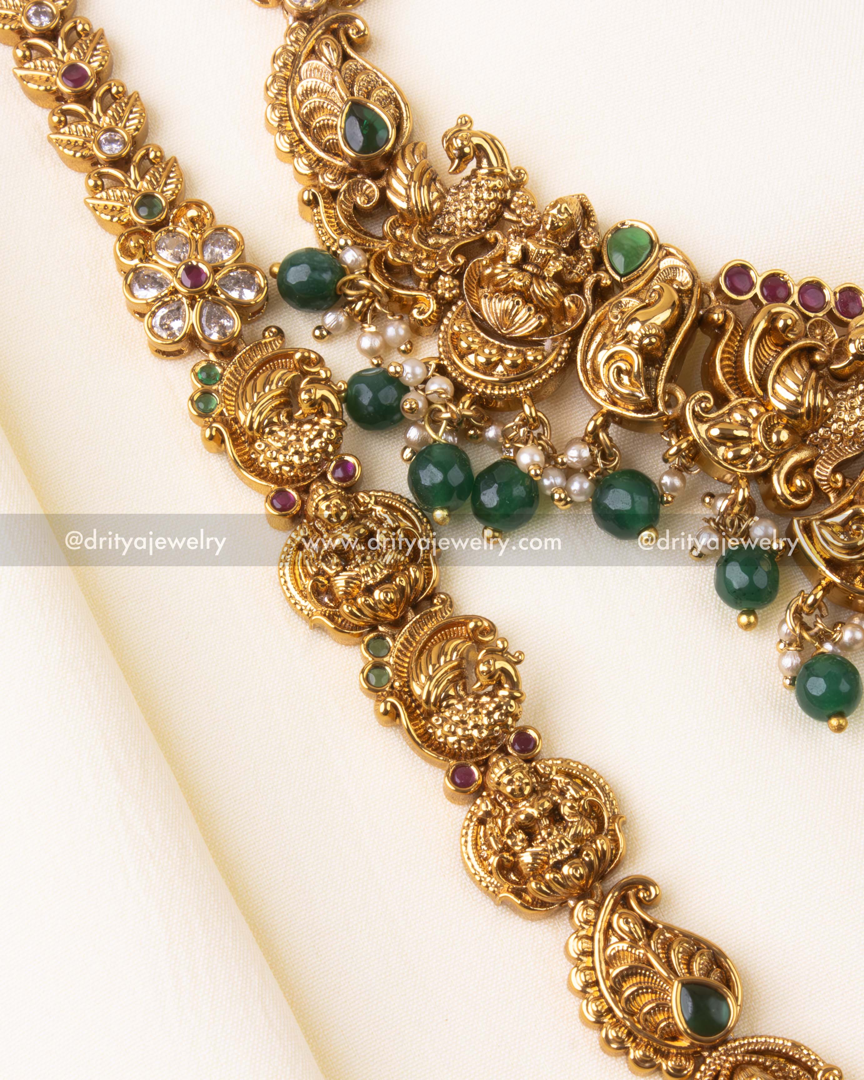 Long necklace with sunburst-style Lakshmi pendant, adorned with green beads and detailed carvings.