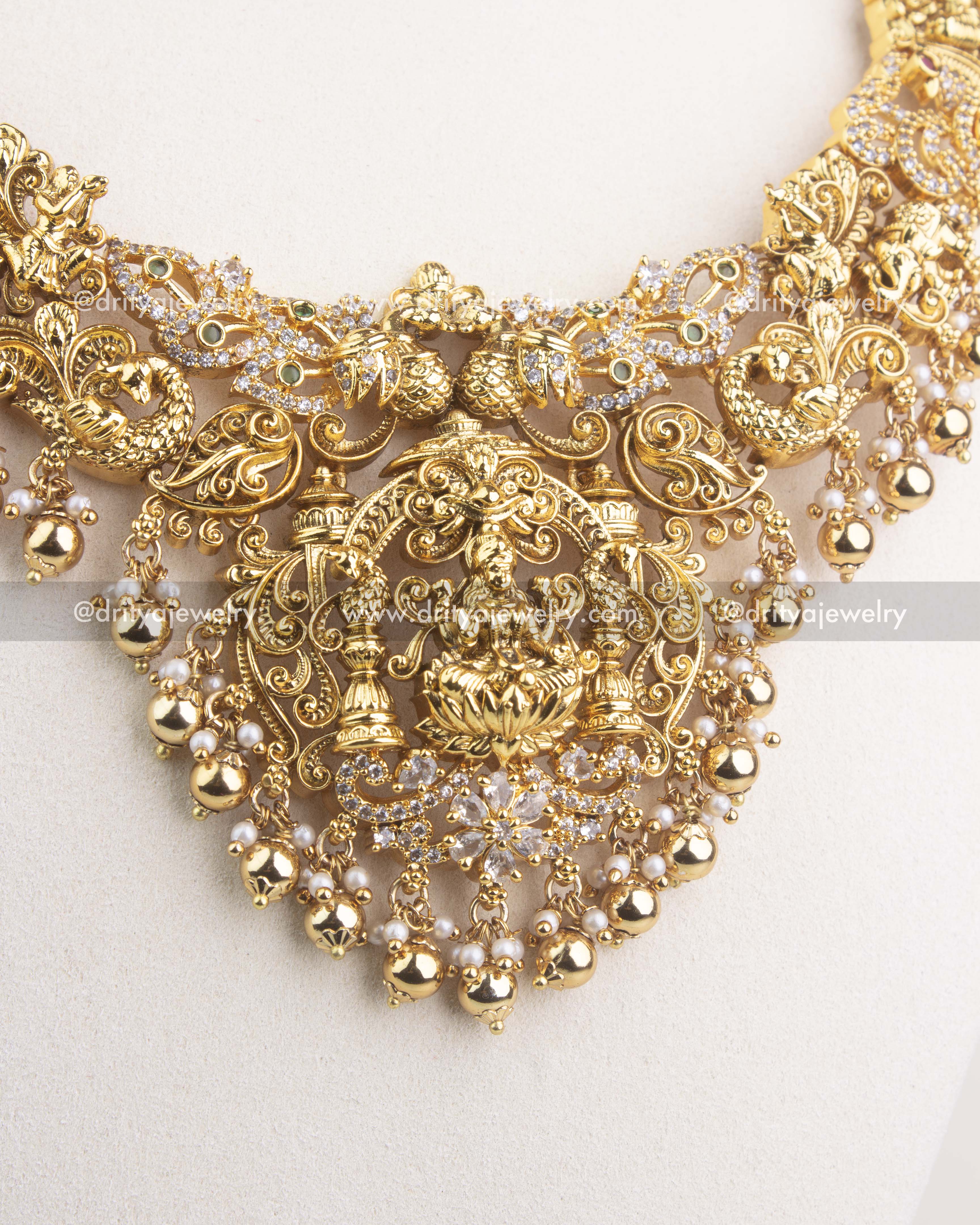Intricate Lakshmi Devi pendant with peacock motifs and Nakshi carving in antique gold finish.