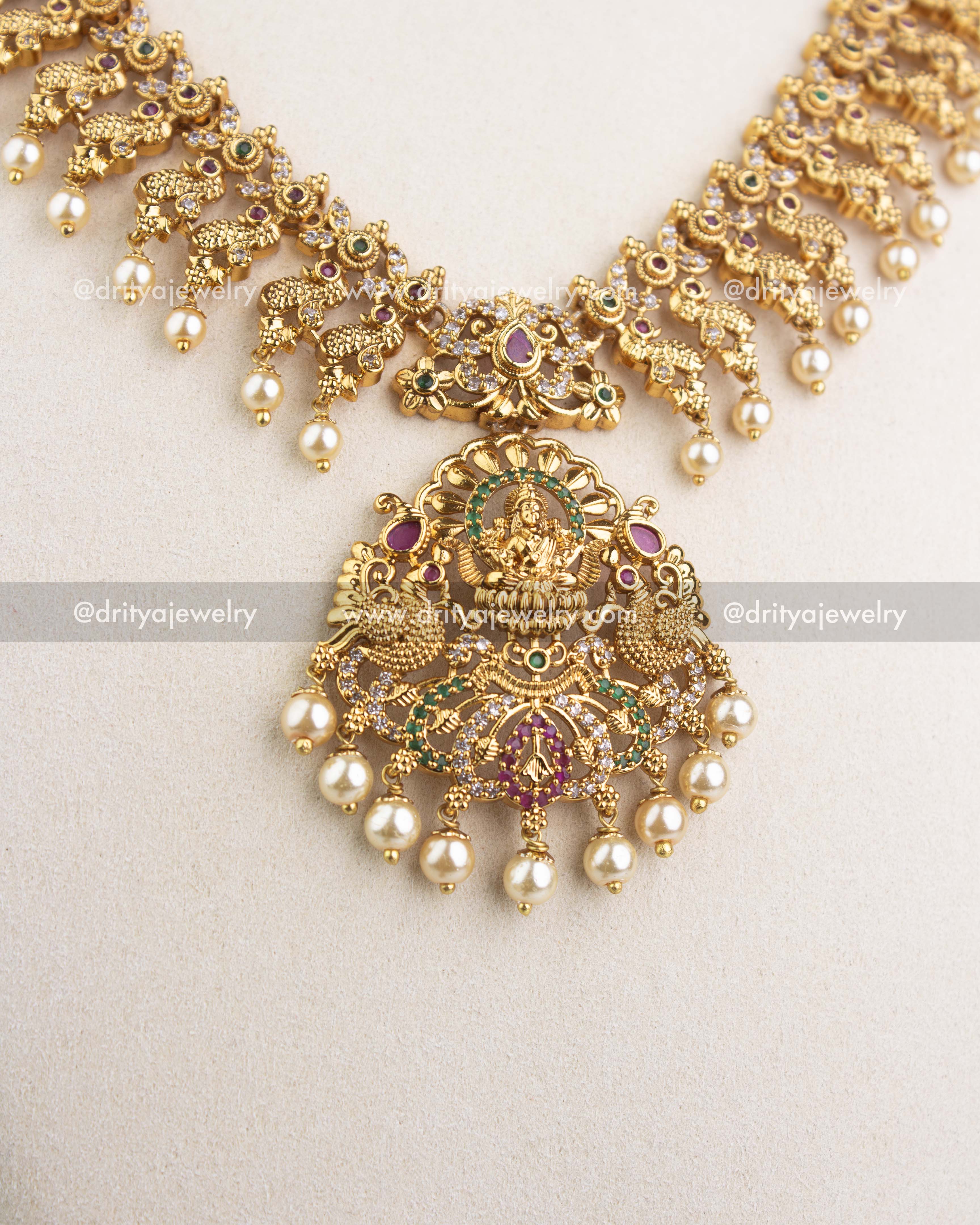 Large goddess Lakshmi pendant with pearl danglers in antique gold finish.