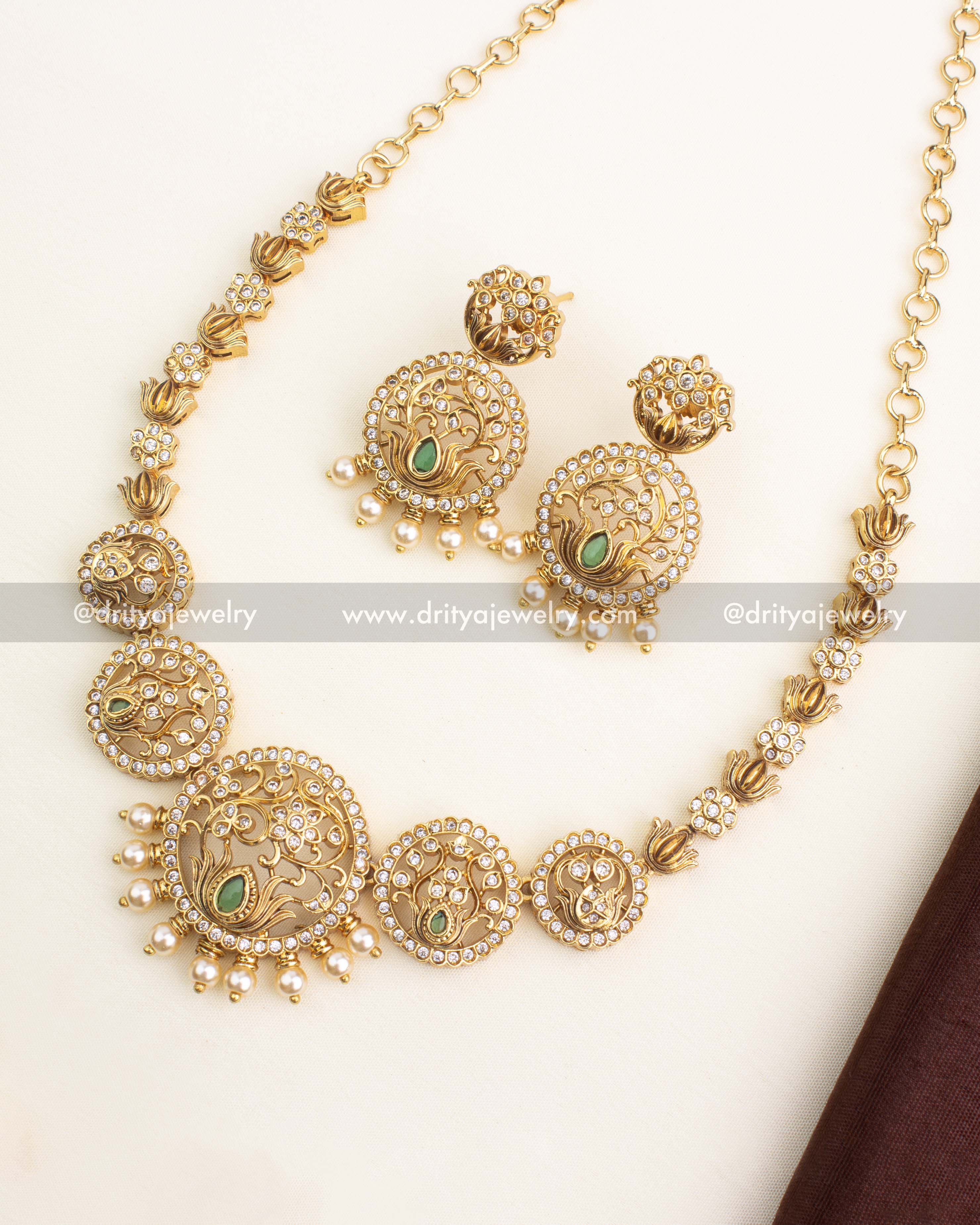 Gold-plated lotus motif short necklace set featuring circular CZ frames, green stone accents, and pearl droplets.