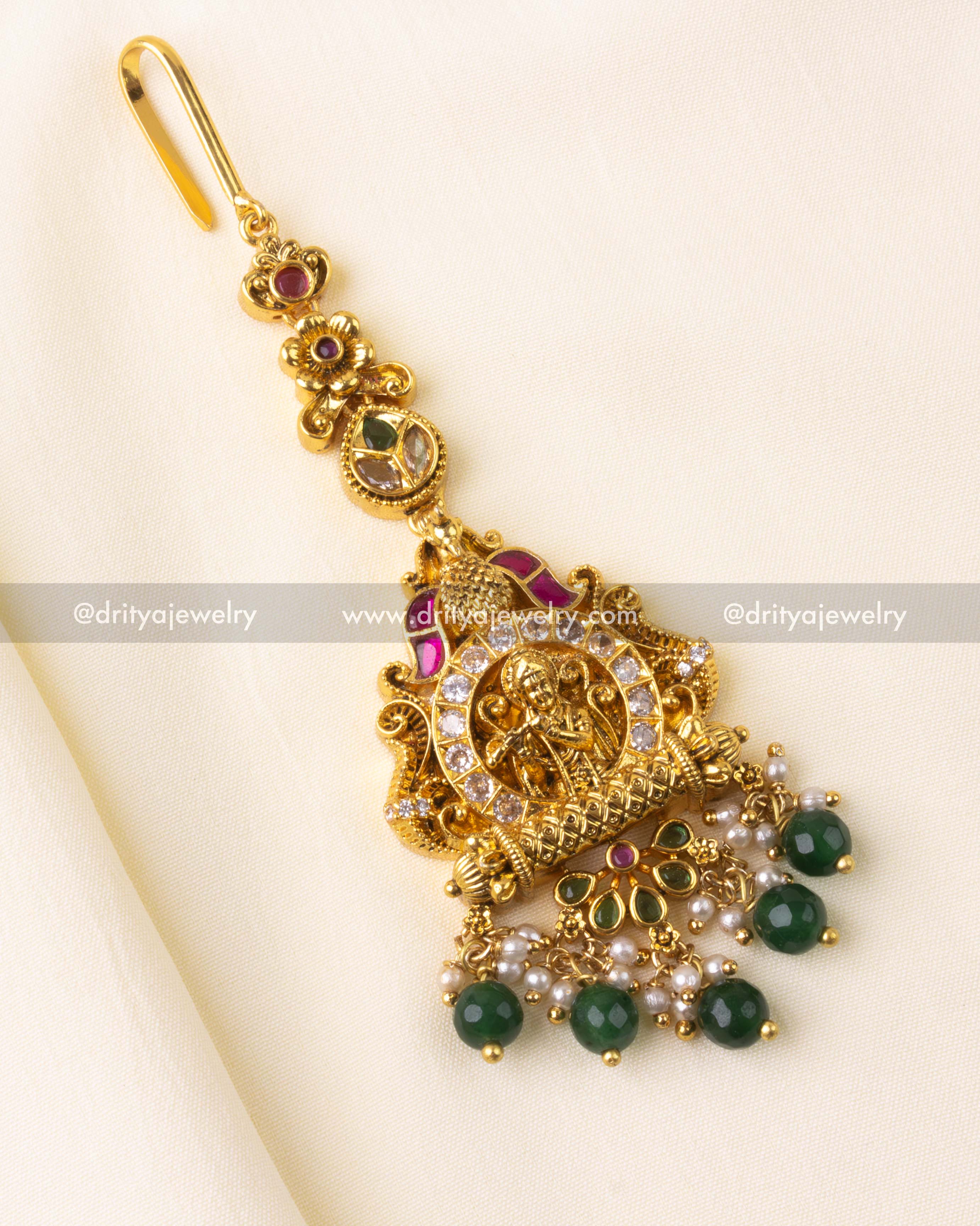 Maang tikka with Lakshmi motif and green kemp stone and pearl danglers.