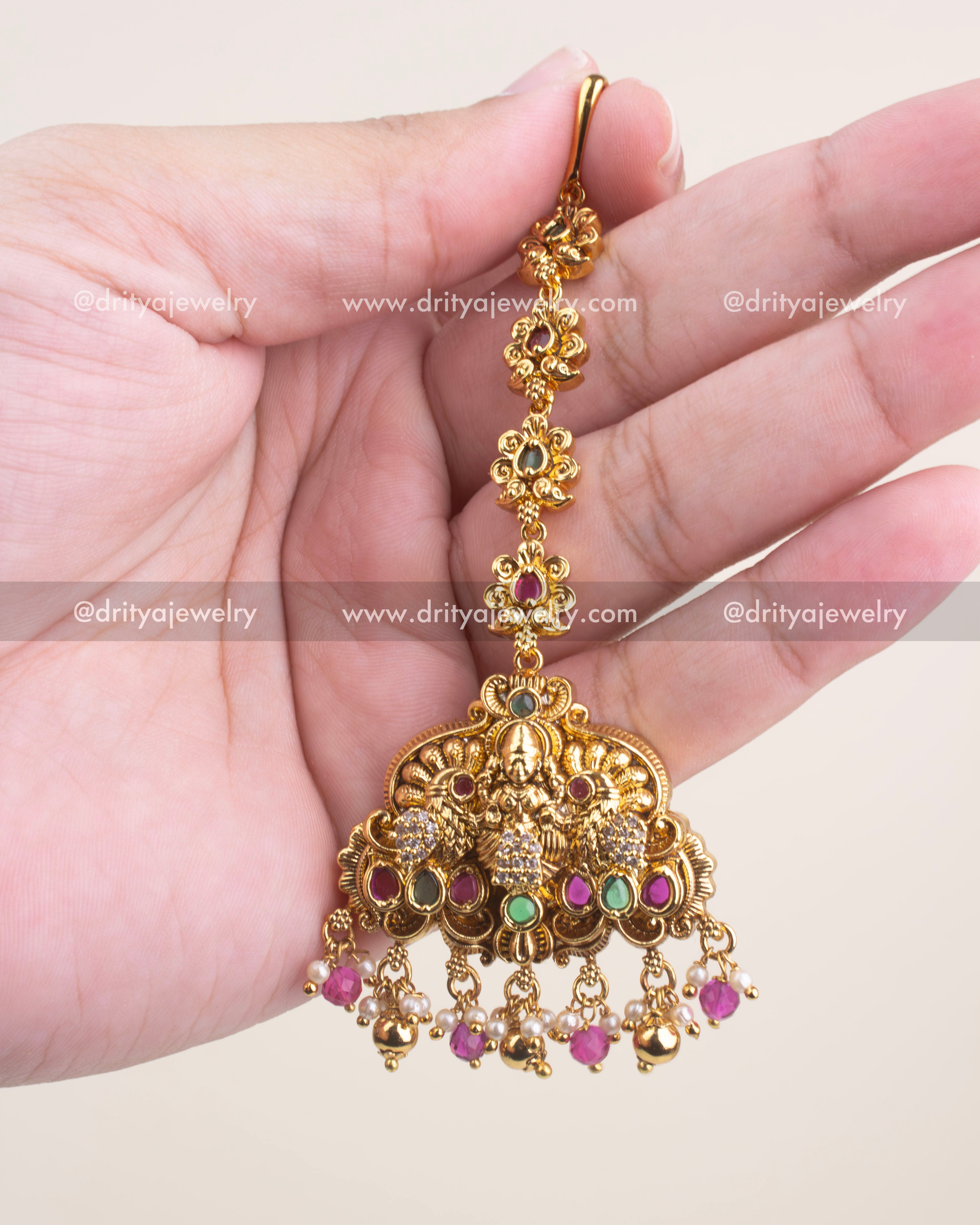 Antique gold maang tikka with CZ stone highlights and ruby pink bead drops.