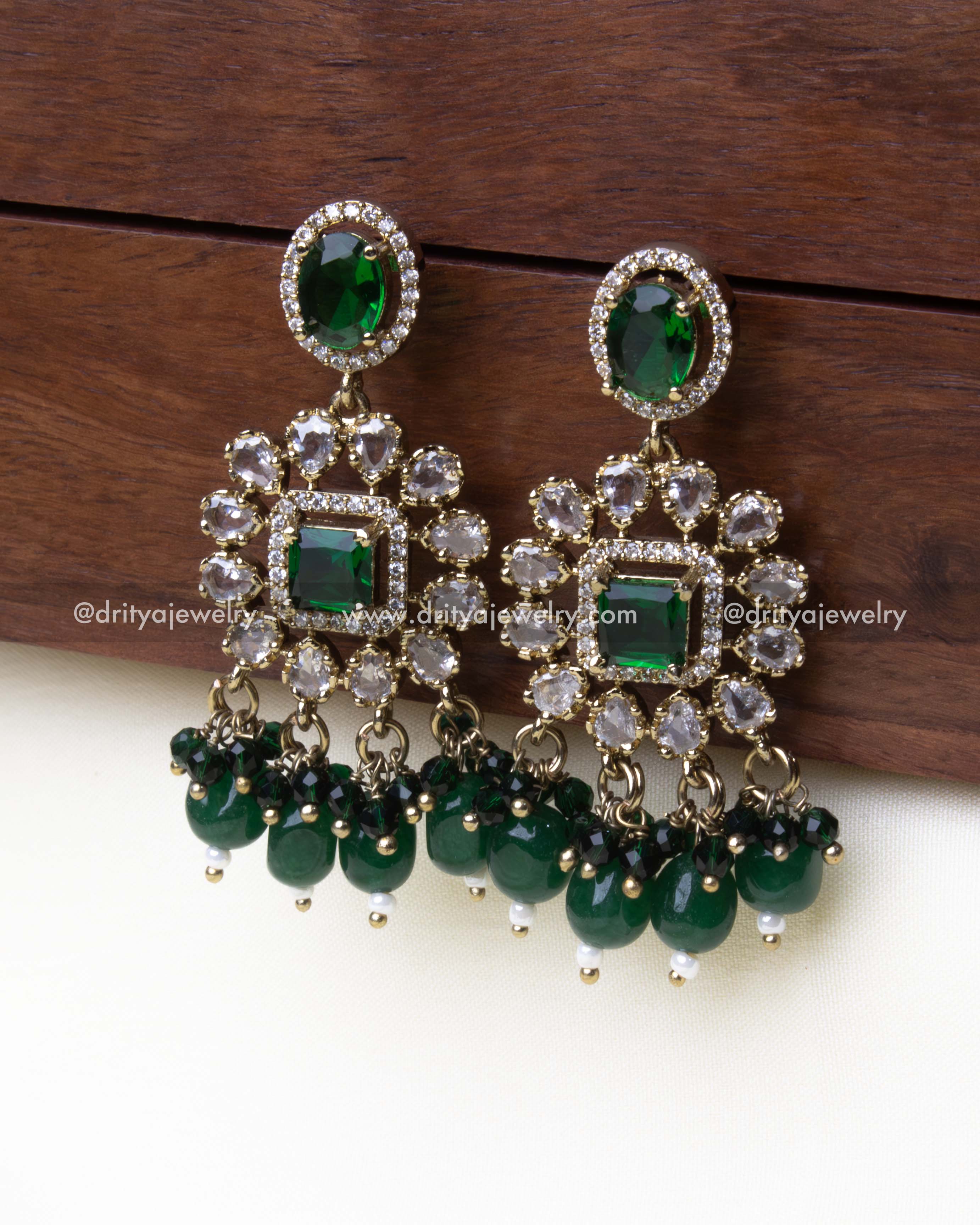 Chandelier-style earrings with emerald beads and AD stones for a luxurious look.