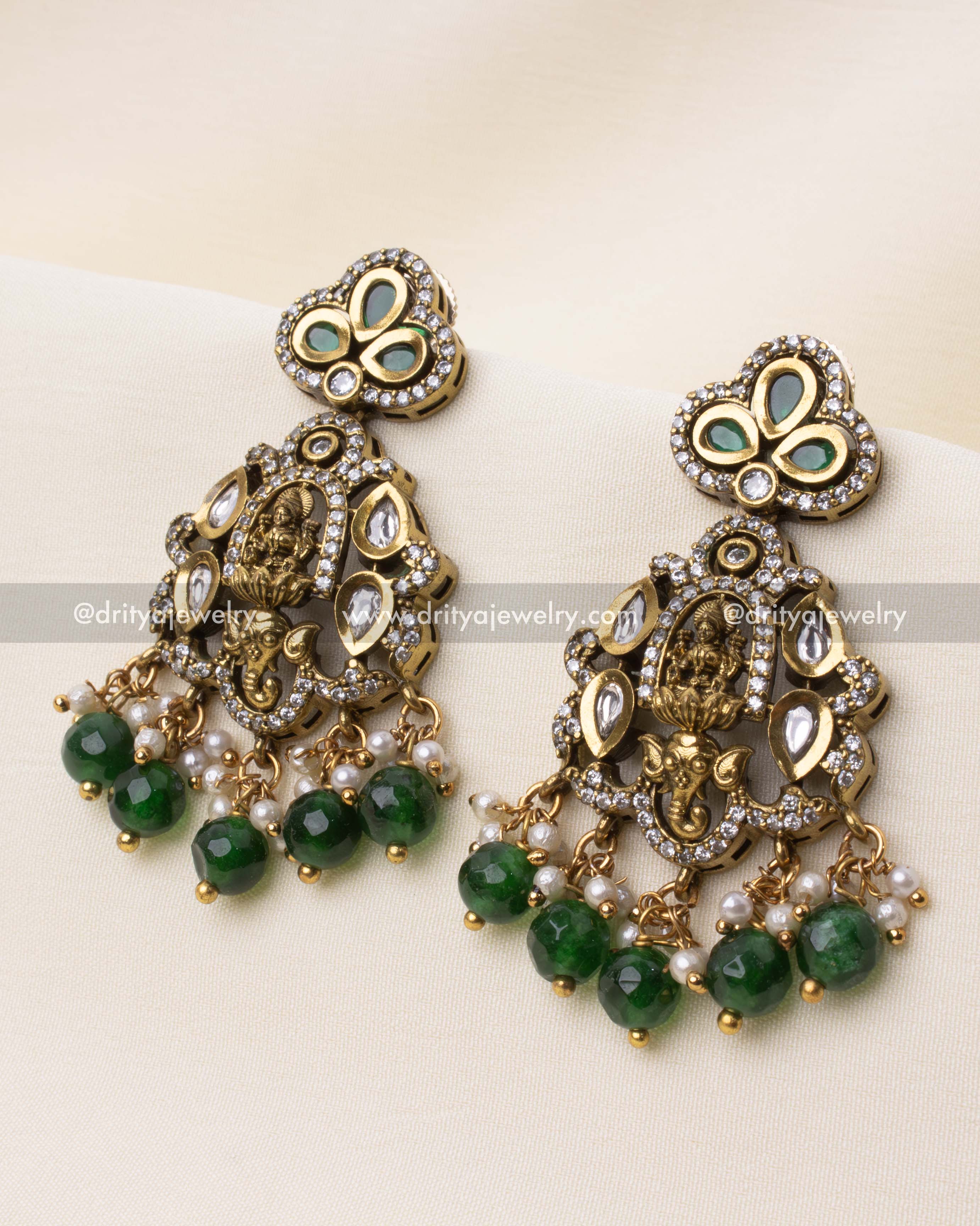 Stunning chandelier earrings featuring a Goddess Lakshmi design, adorned with polki stones and emerald beads.