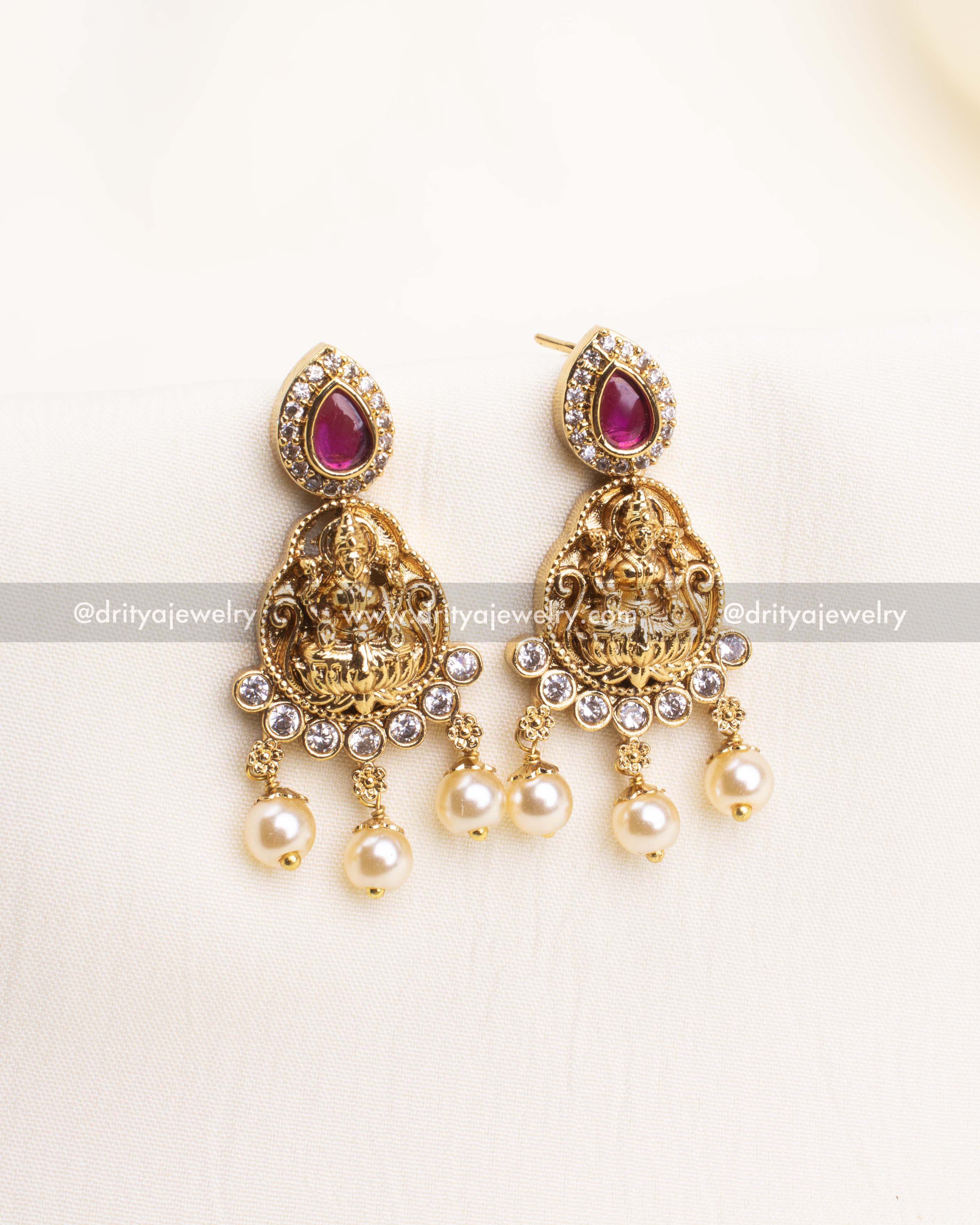 Antique gold earrings with Lakshmi figure, CZ border, and pearl drop accents.