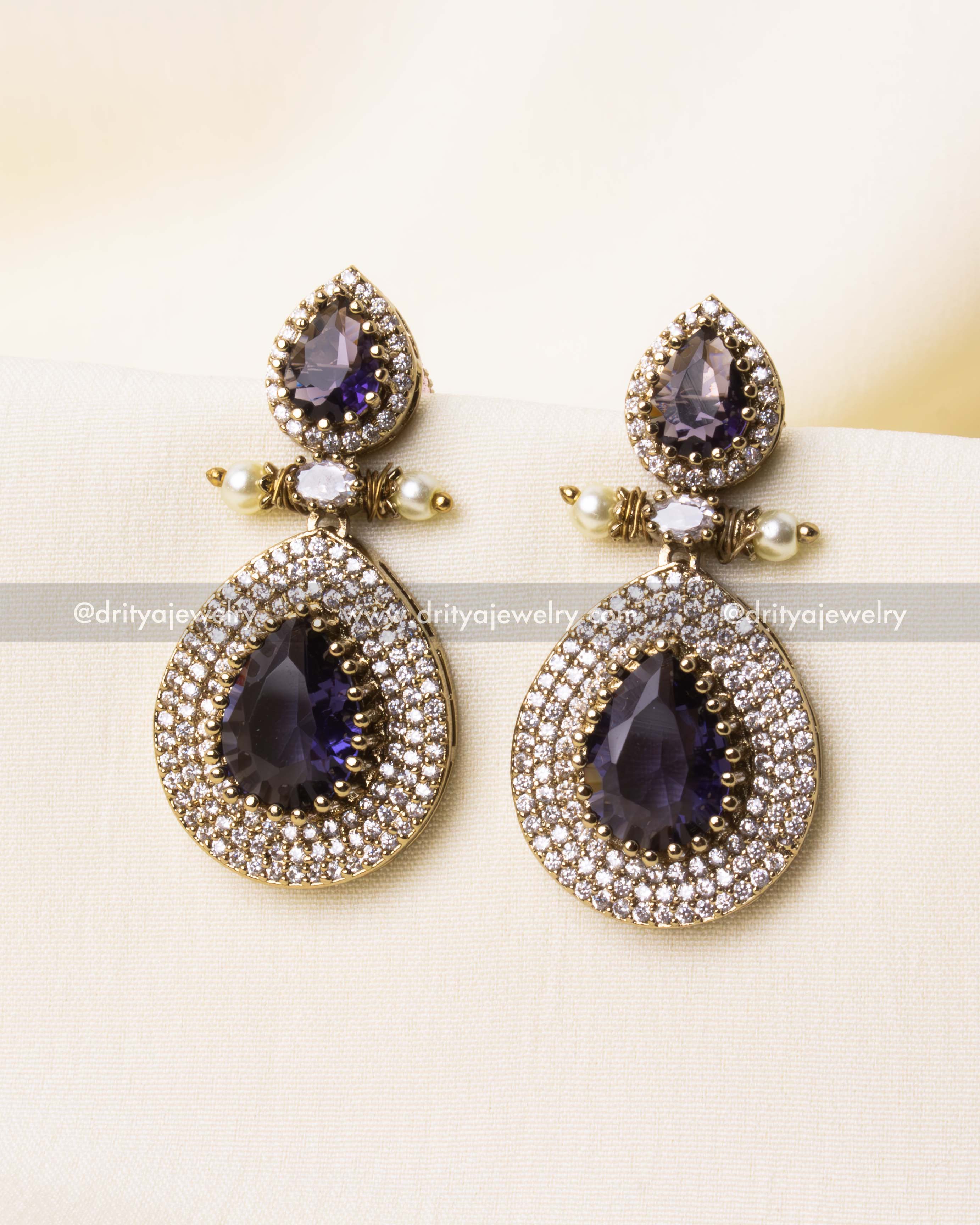 Elegant teardrop earrings featuring deep purple gemstones and sparkling AD stones.
