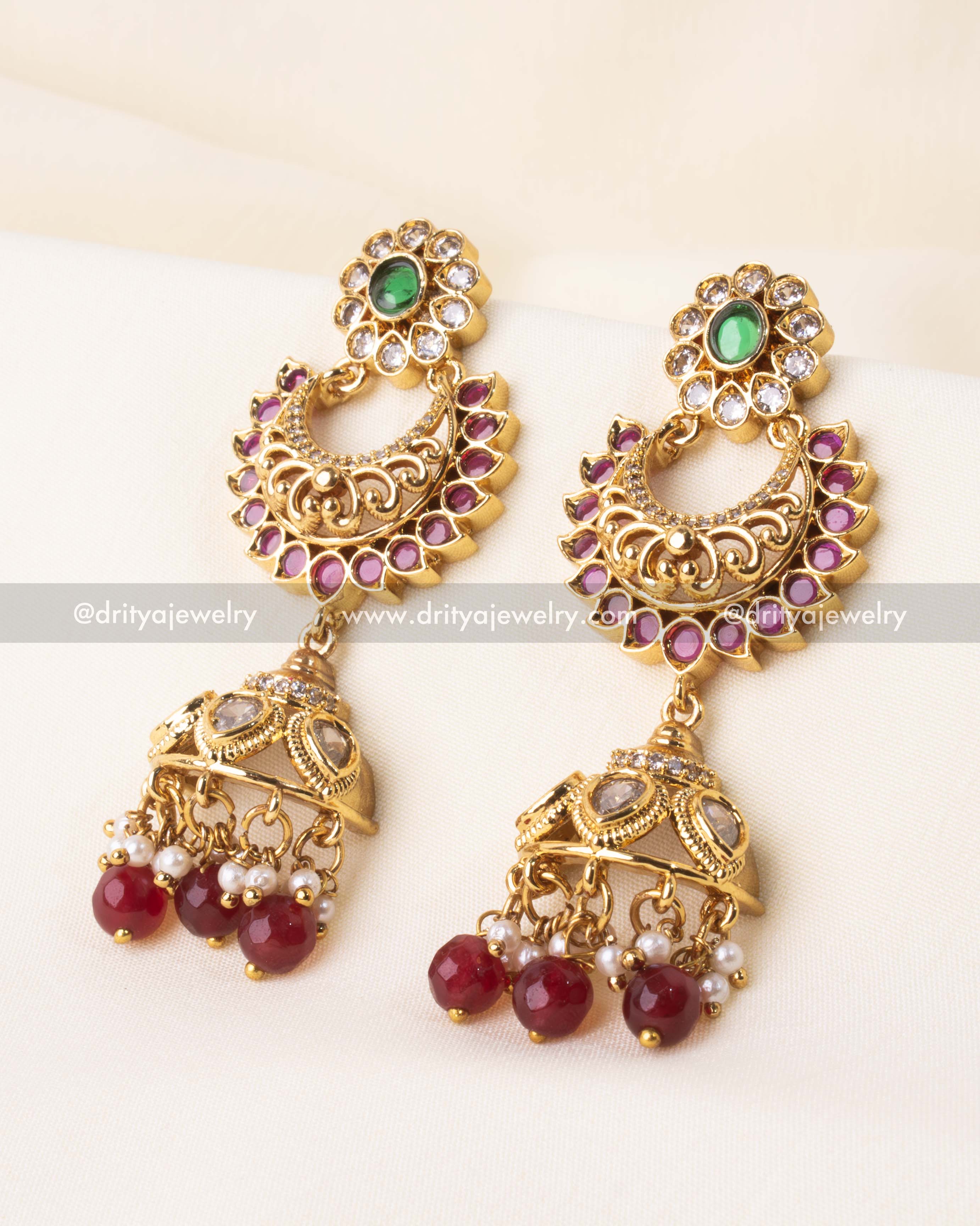 Temple-style earrings with crescent detailing, green stones, and hanging ruby bead jhumkas.