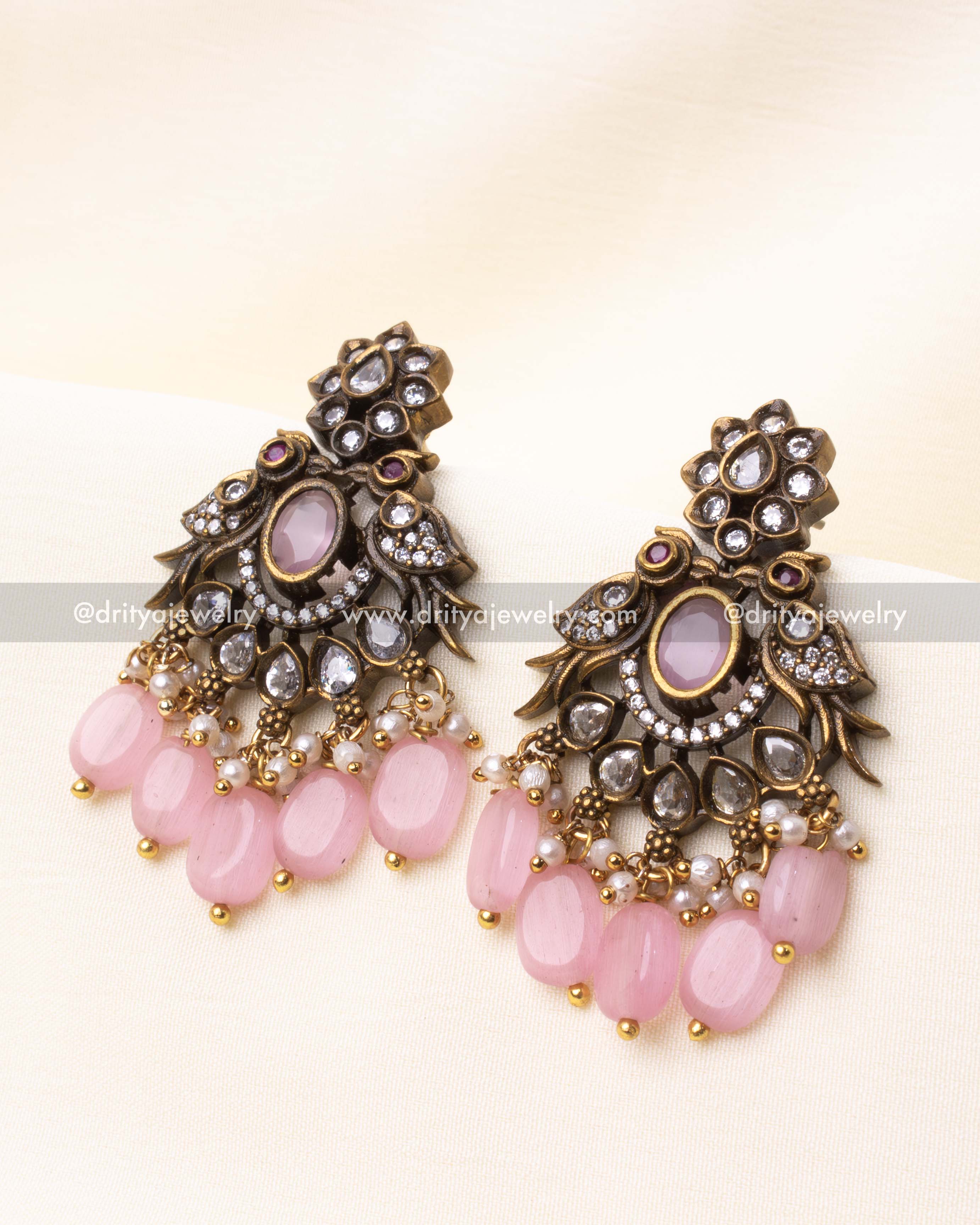 Close-up of Victorian-style earrings adorned with pink stones, CZ detailing, and pink bead drops.