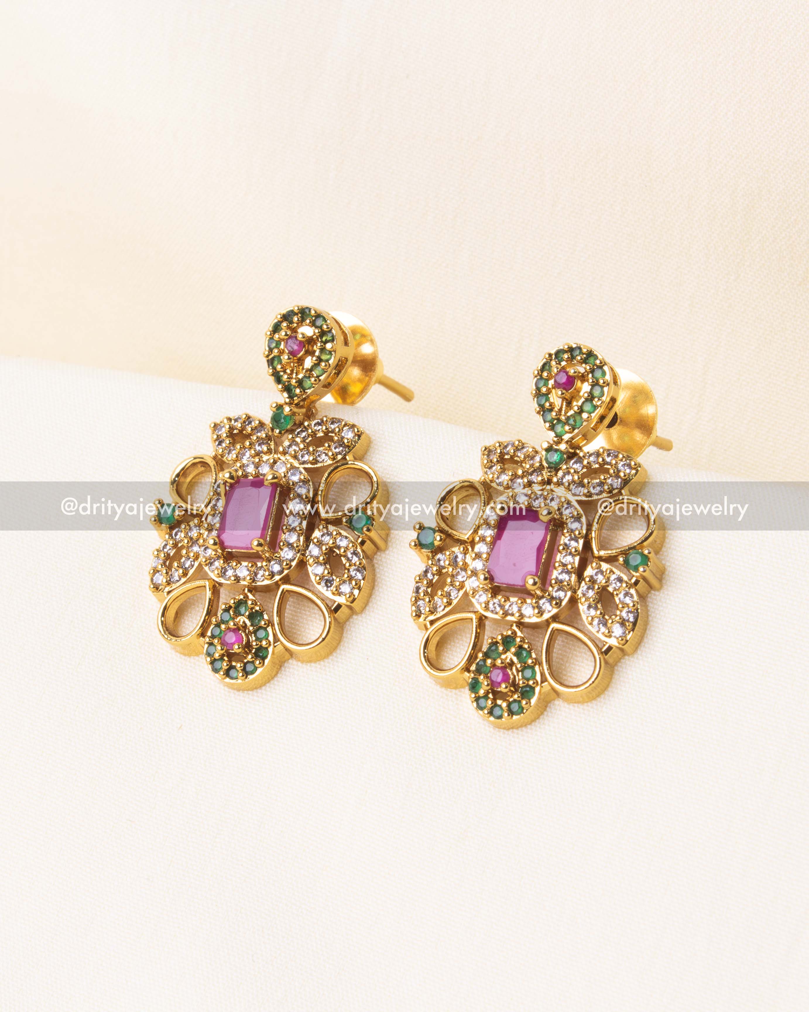 Close-up of floral earrings with pink and green accents and gold-plated detailing.