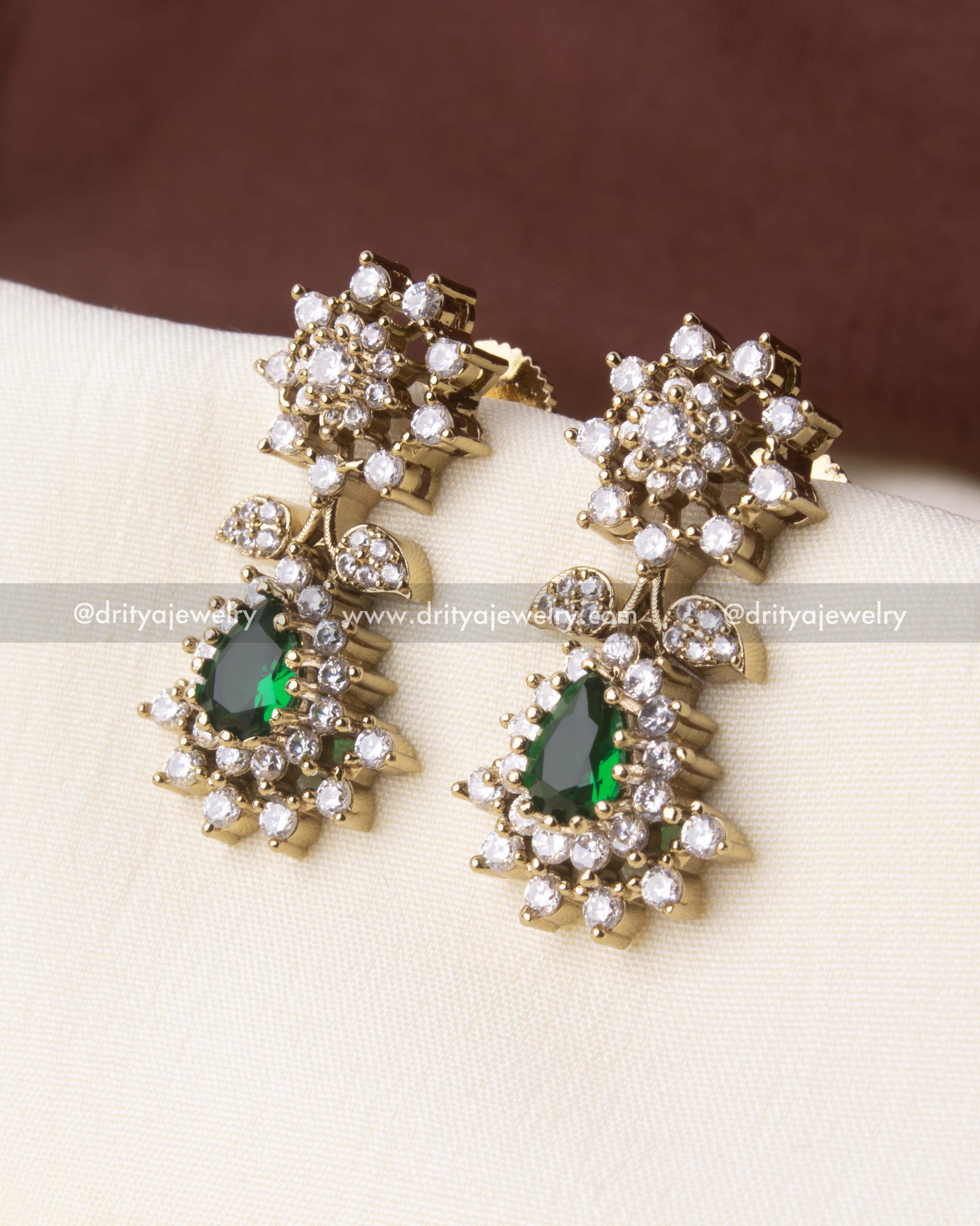 Elegant earrings featuring green center stones and CZ-studded floral patterns, matching the necklace set.