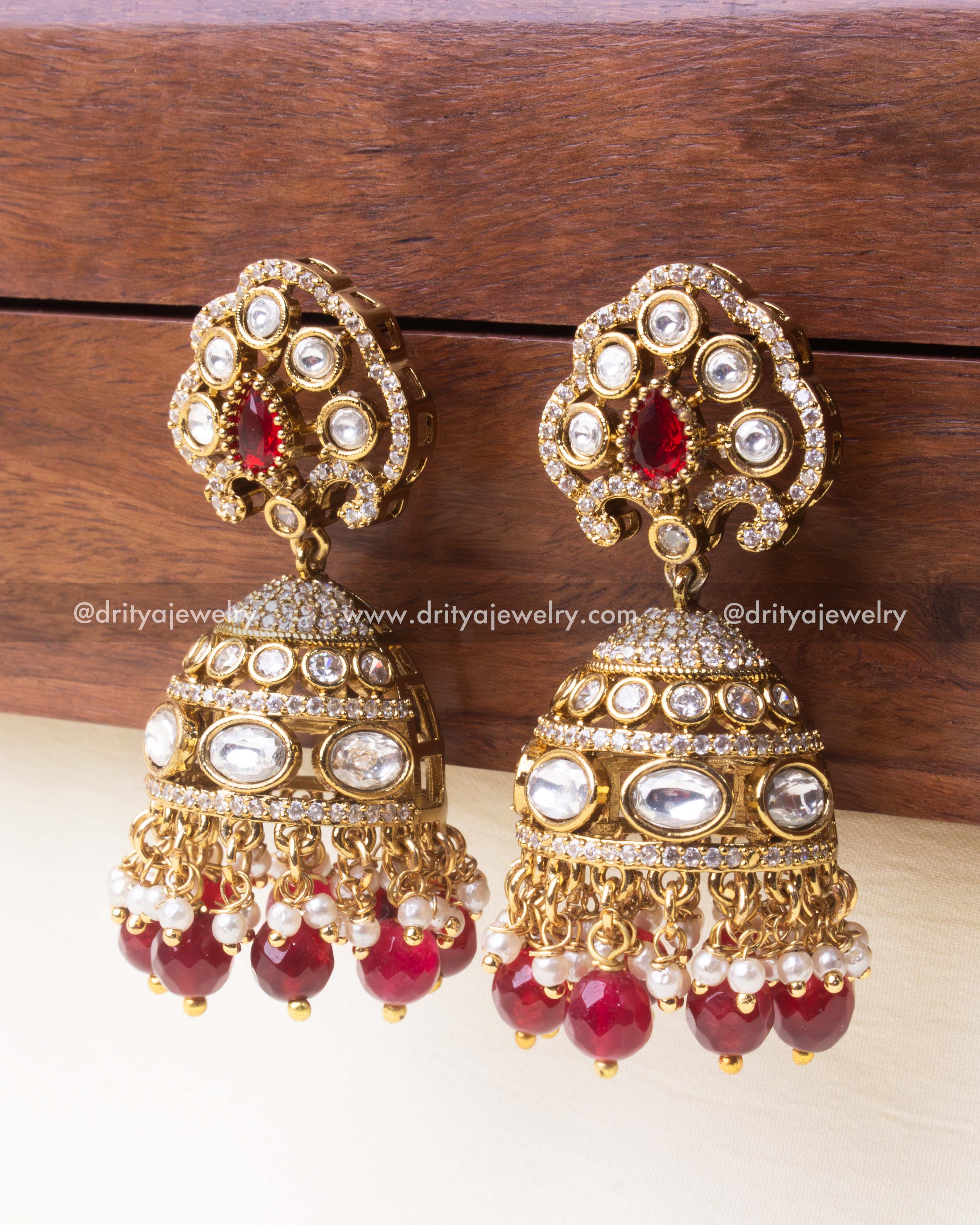 Traditional gold-plated jhumka earrings featuring polki Kundan work and ruby-red drop beads.