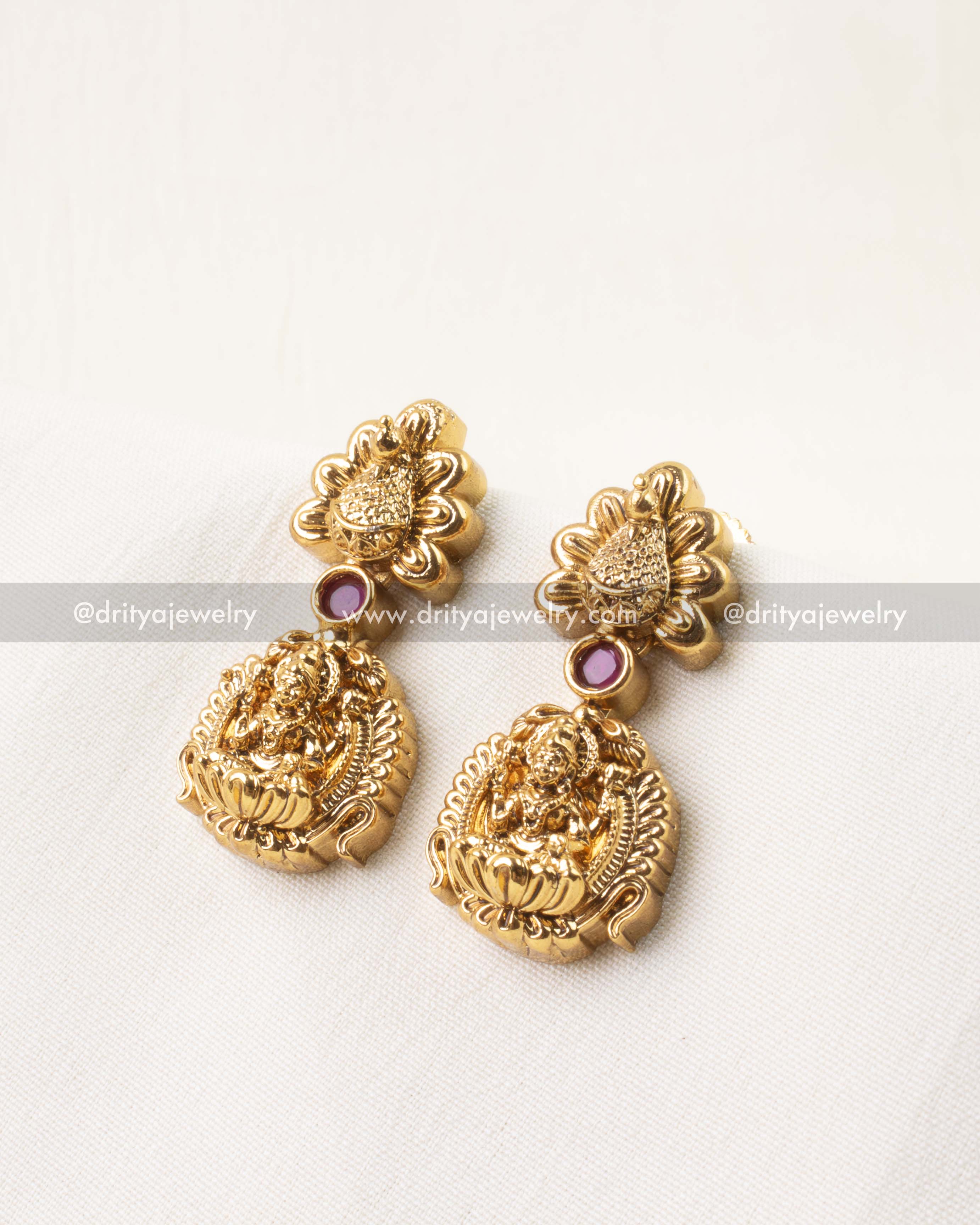 Pair of antique temple-style earrings with Lakshmi motifs and ruby stone detailing.