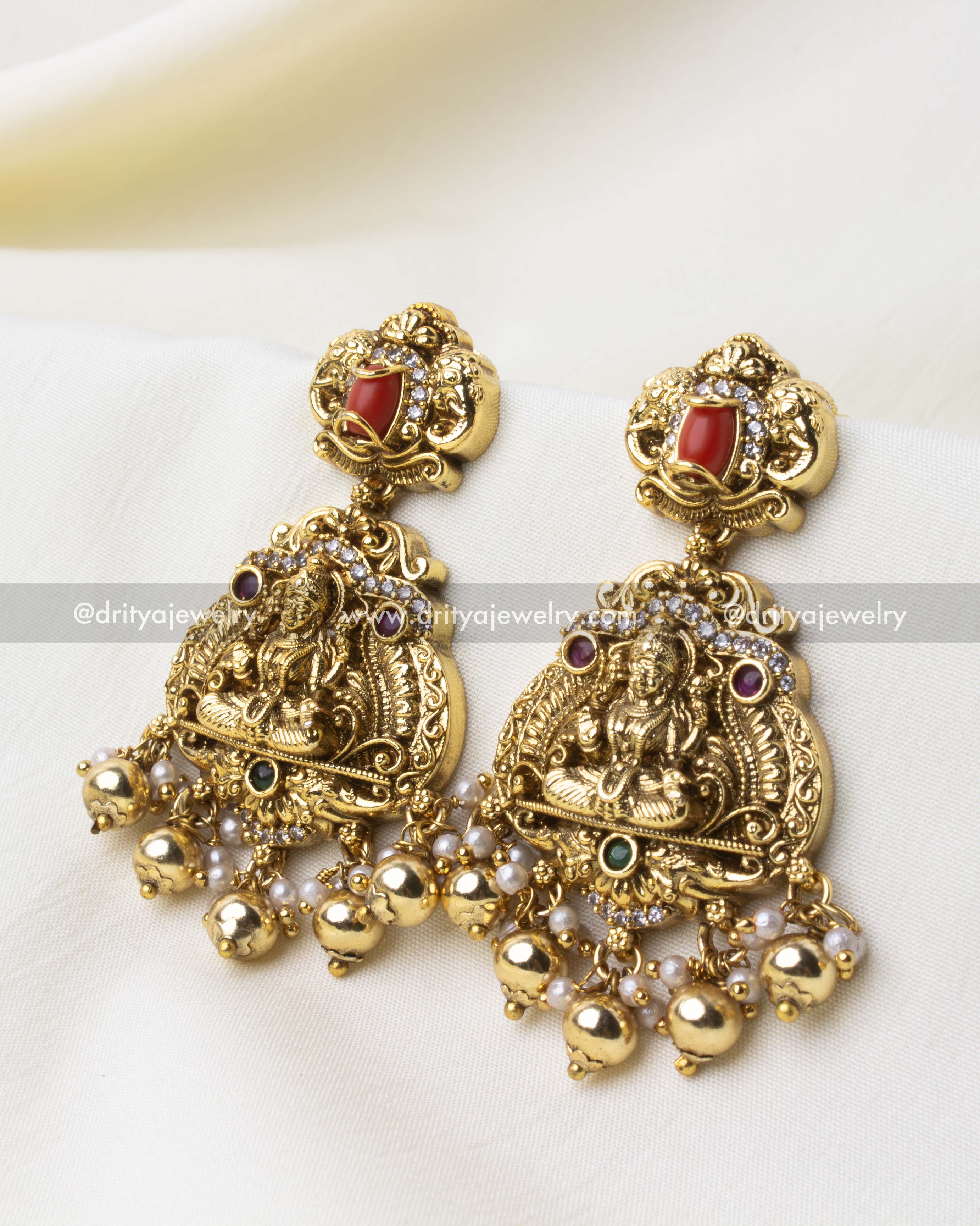 Pair of Nakshi jhumka-style earrings with deity motifs and pearl accents.