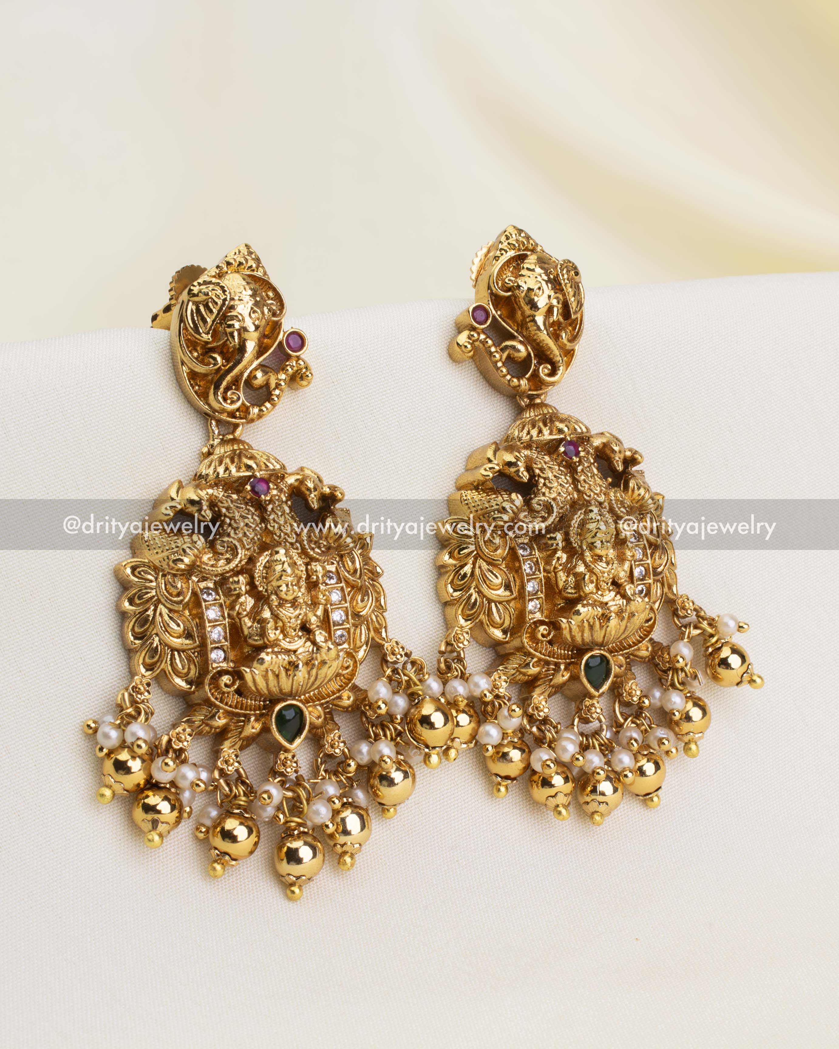 Pair of nakshi temple earrings with goddess motif, elephant stud top, and coordinated pearl-gold bead danglers.