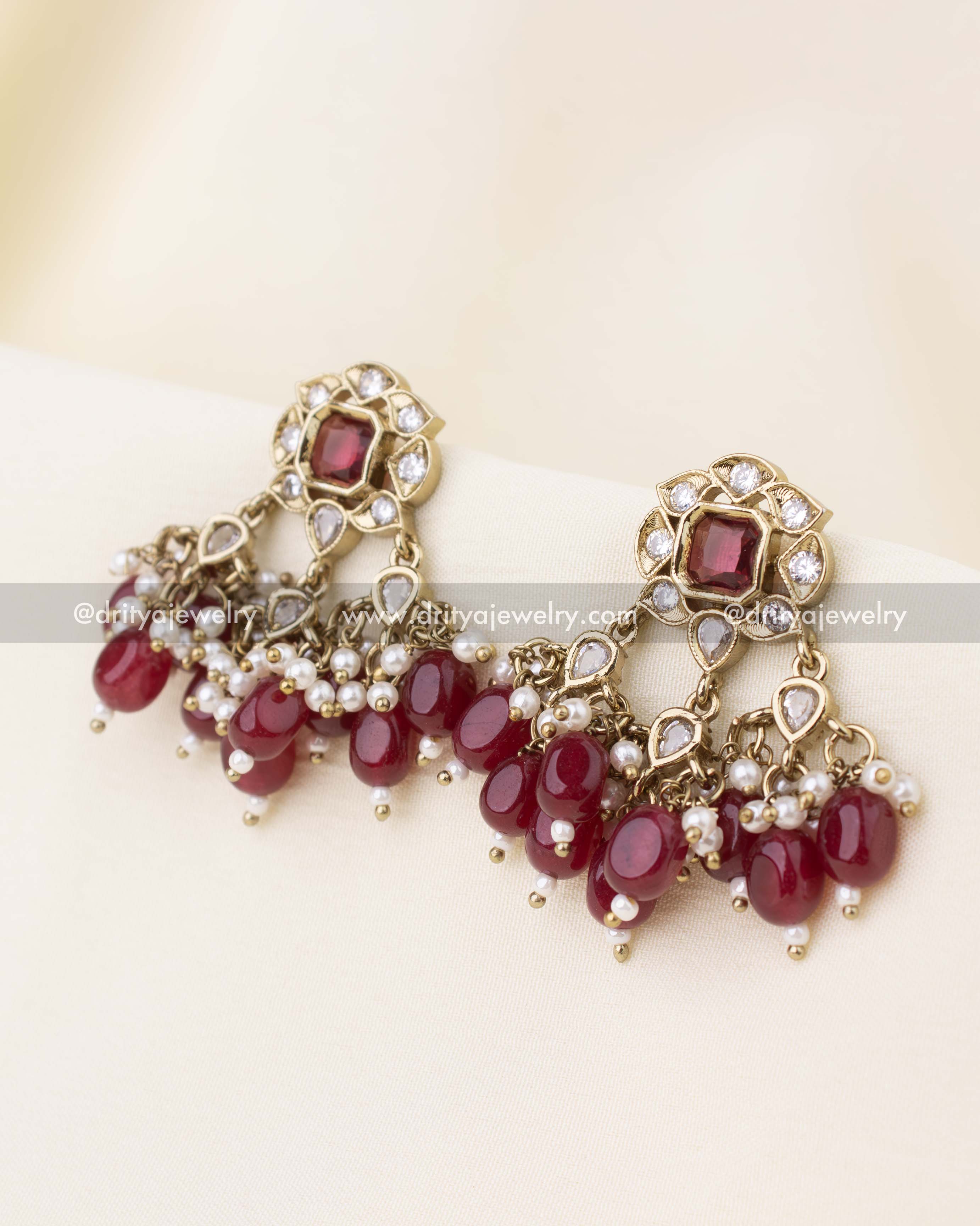 Stud earrings featuring red stones and dangling ruby bead accents.