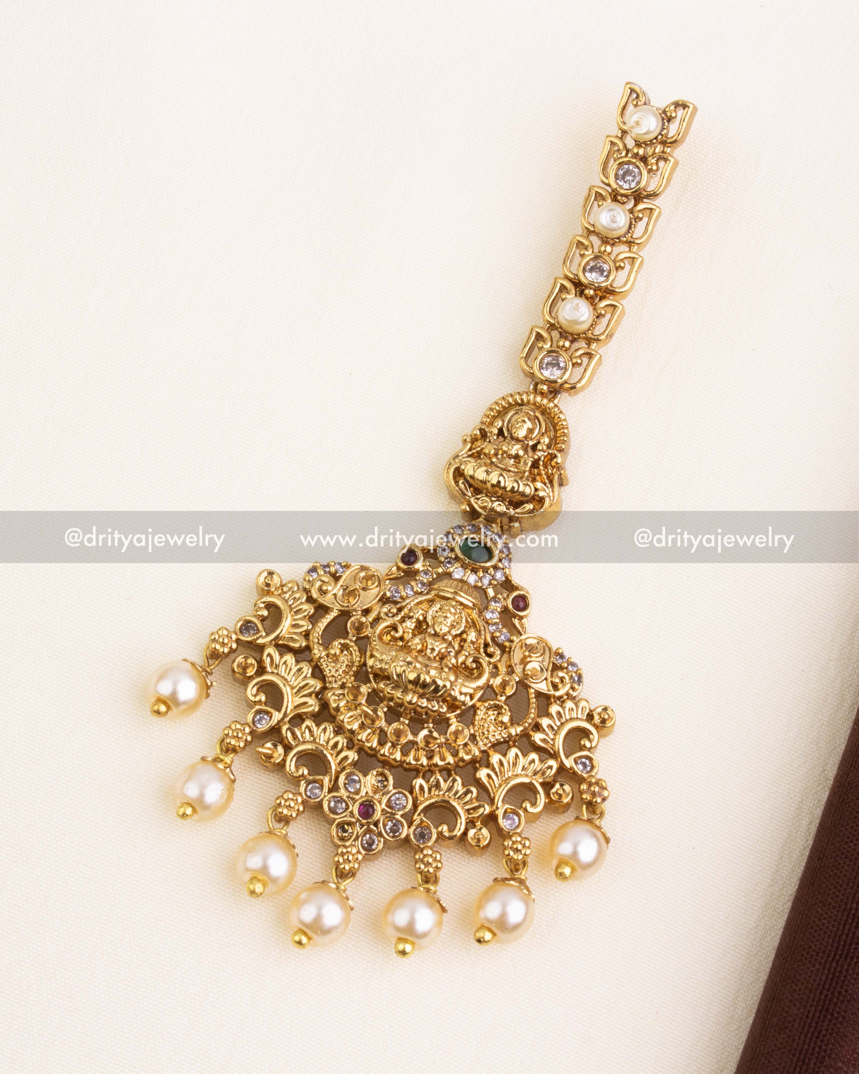 Gold-plated maang tikka with Lakshmi Devi figure, CZ stones, and pearl hangings to match the temple jewelry set.