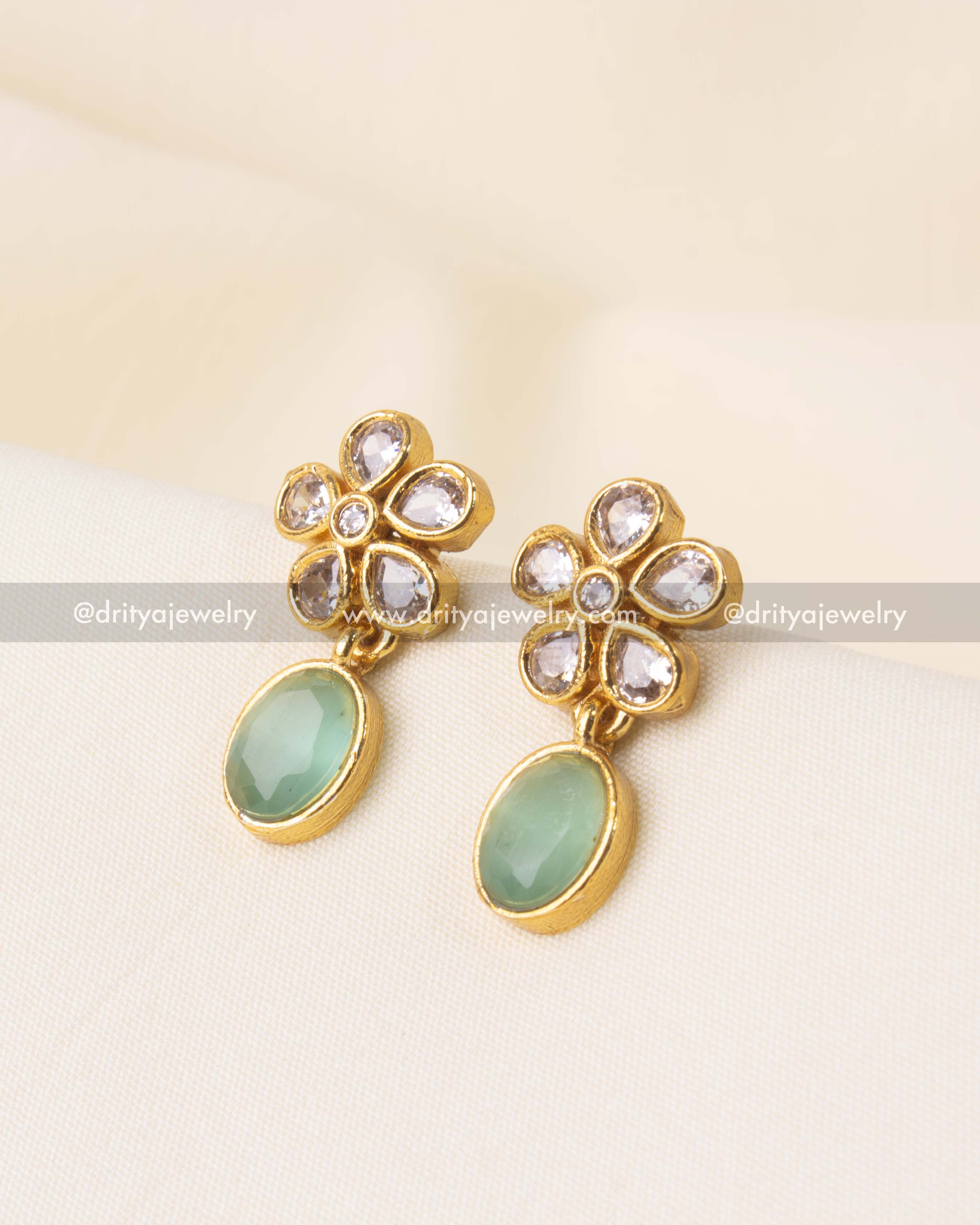 Stud earrings with kundan floral motif and emerald green teardrop stone.