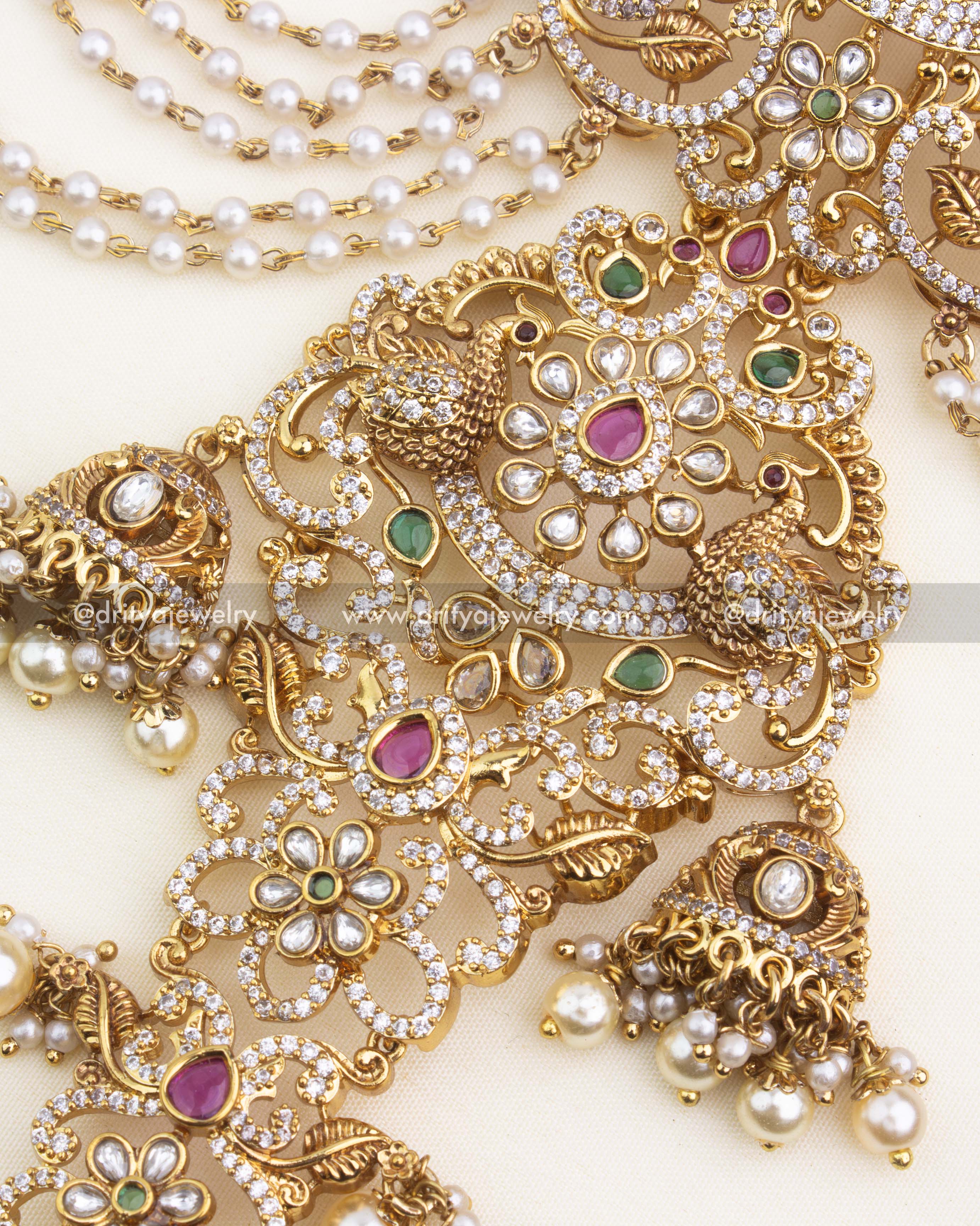 Close-up of top floral and peacock motifs with ruby and emerald kundan stones.